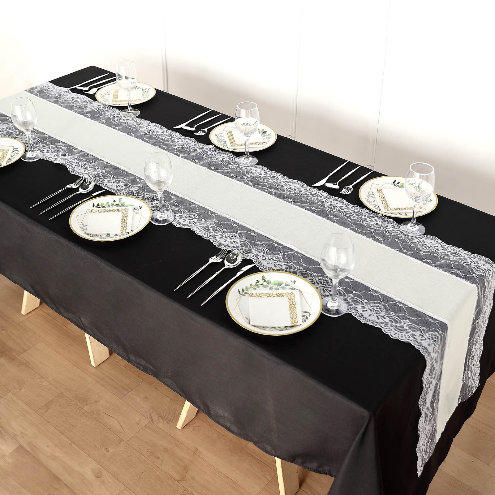 Ivory burlap table runner with white lace edging on a black table setting.