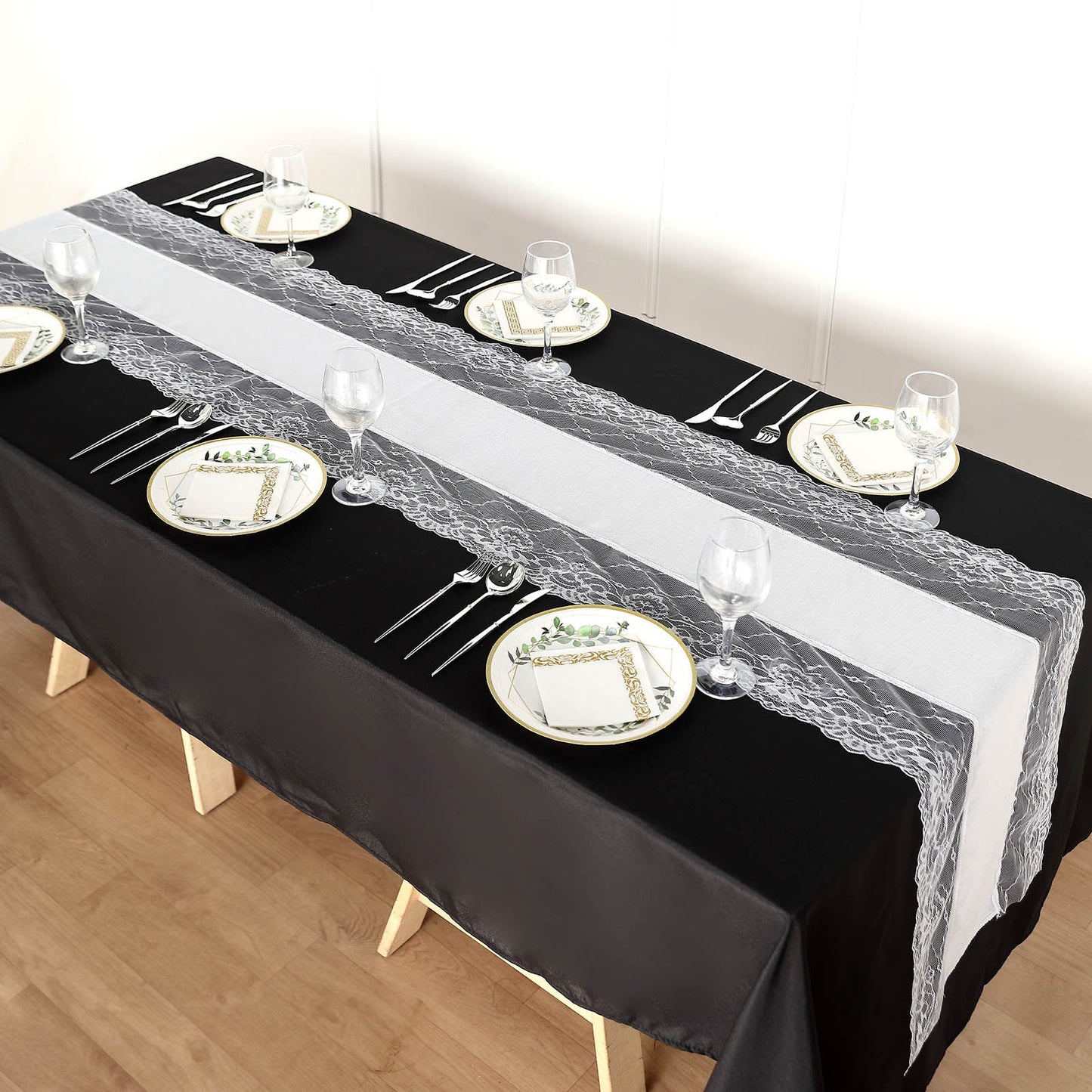 White faux burlap table runner with lace edging on a black table.