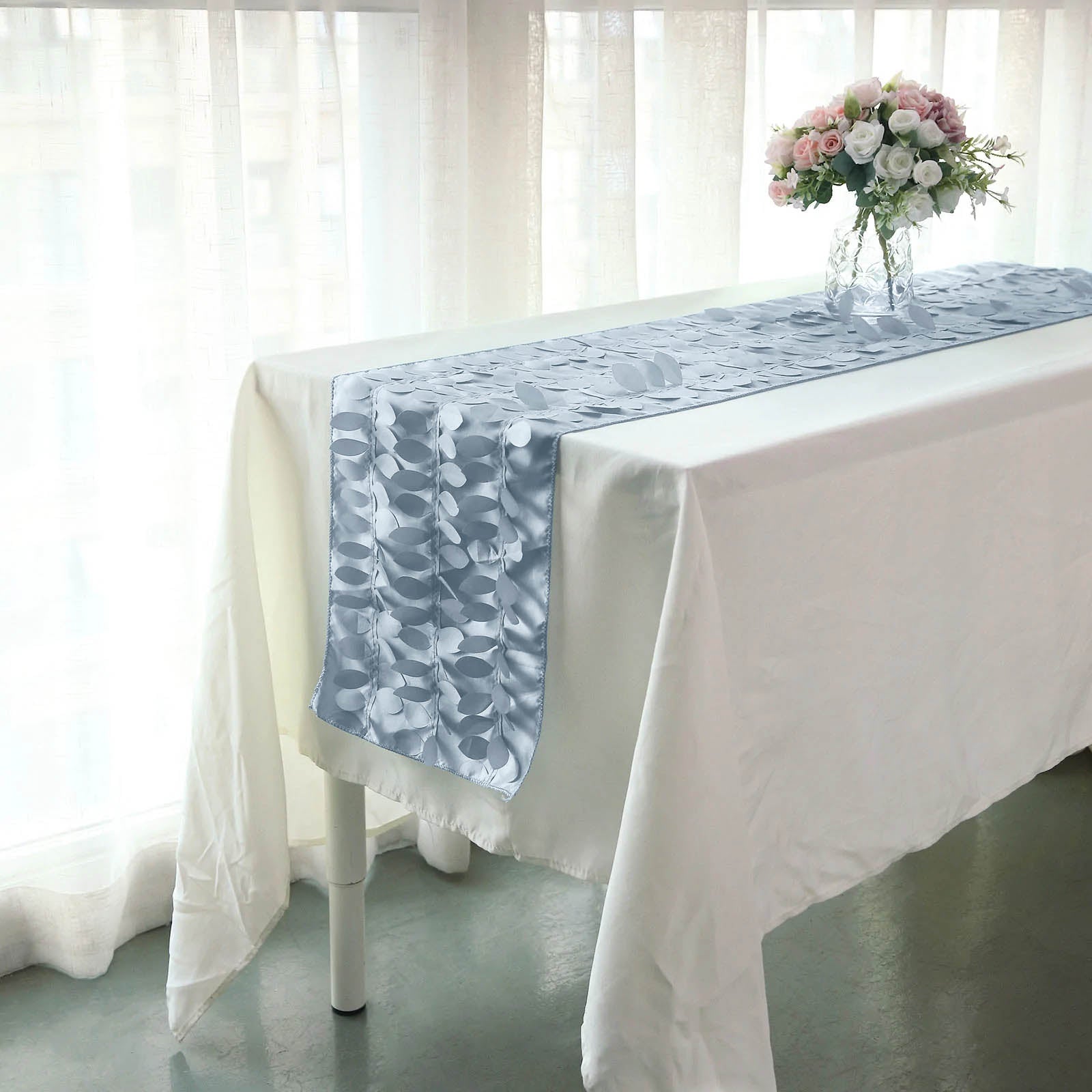 Dusty blue 3D leaf petal taffeta fabric table runner on a white table.