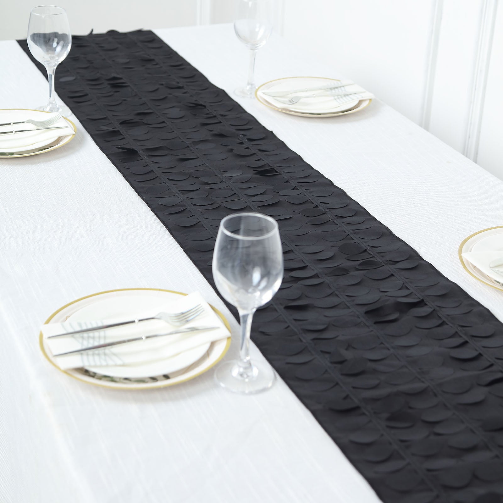 Black 3D leaf petal taffeta fabric table runner on a white table.