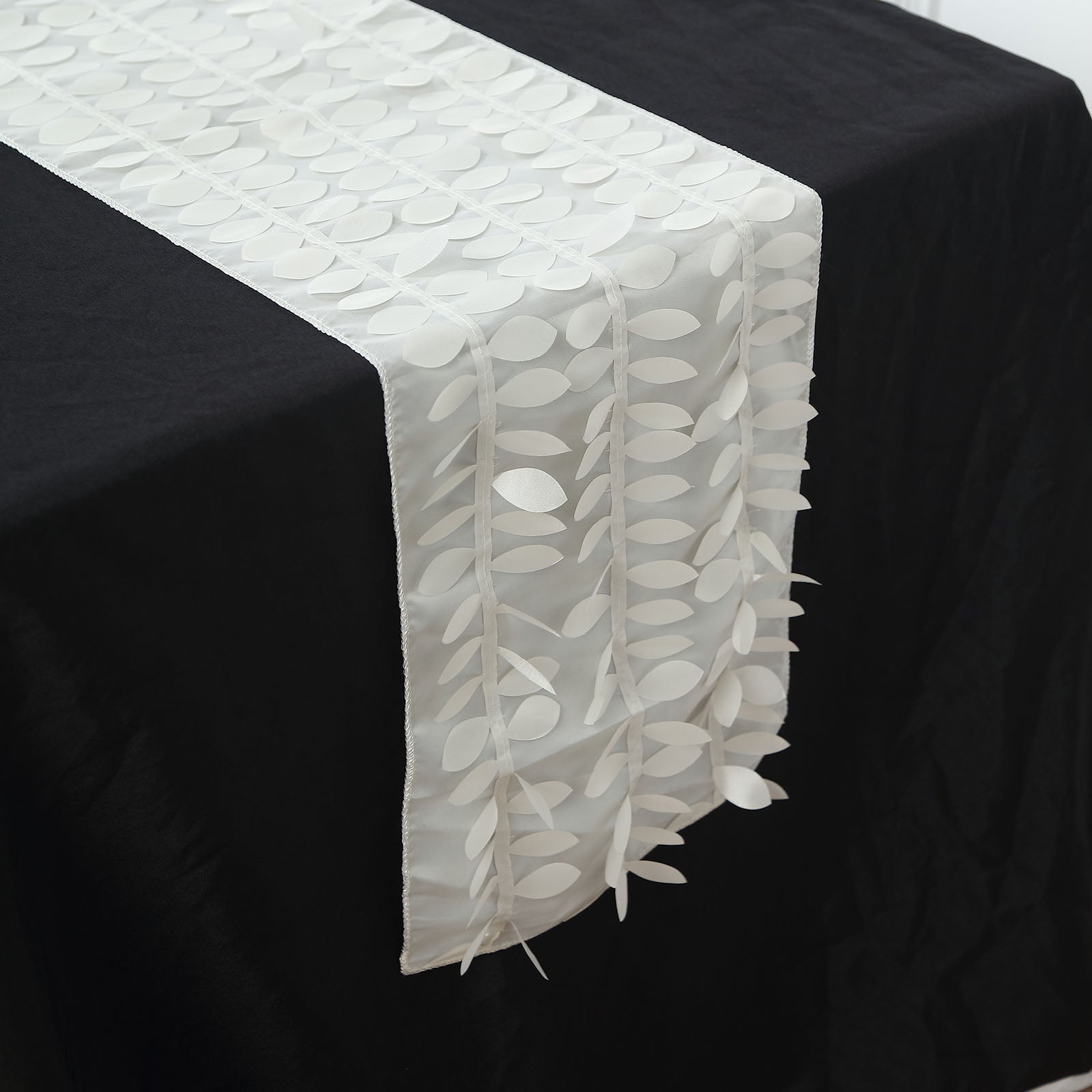 Ivory 3D leaf petal taffeta table runner on a black tablecloth.
