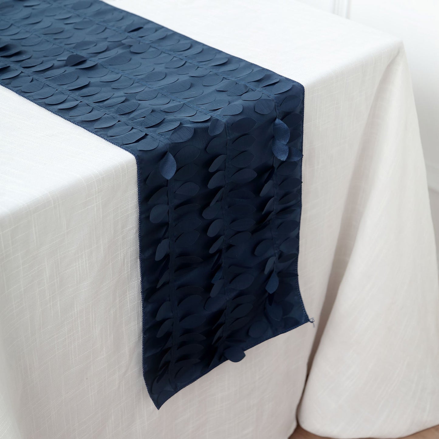 Navy blue 3D leaf petal taffeta fabric table runner on a white table.