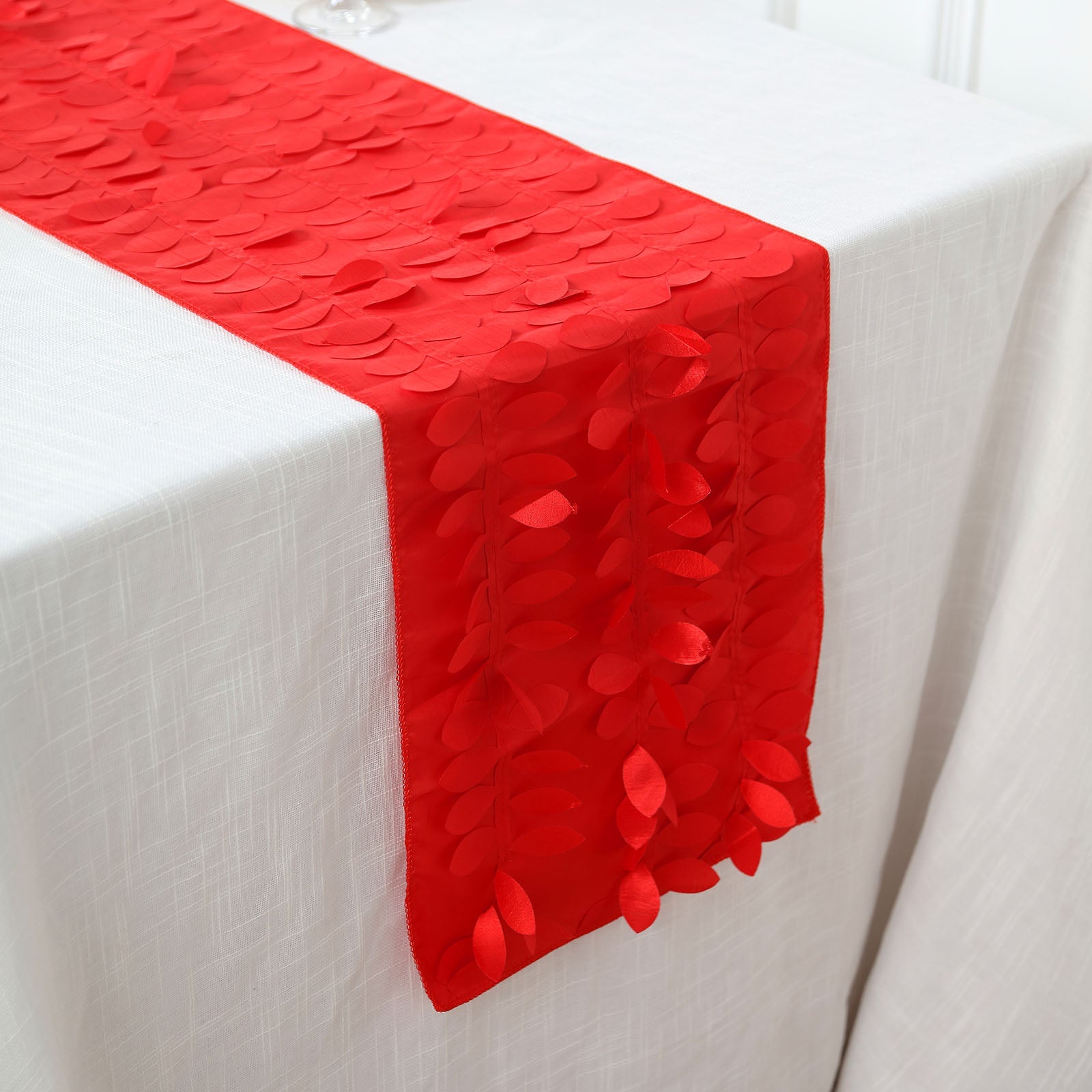 Red 3D leaf petal taffeta fabric table runner on a white table.