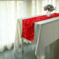 Red 3D leaf petal taffeta fabric table runner on a white table.