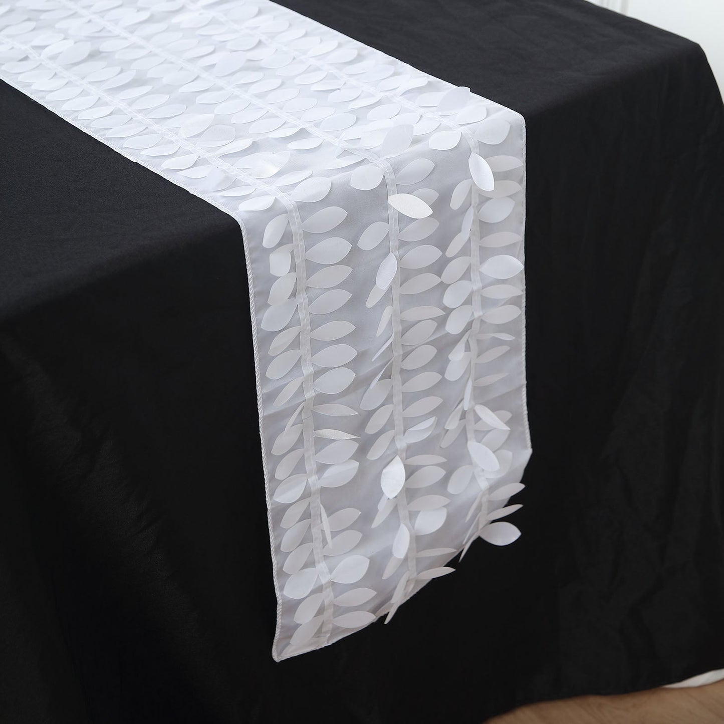 White 3D leaf petal taffeta fabric table runner on a black table.