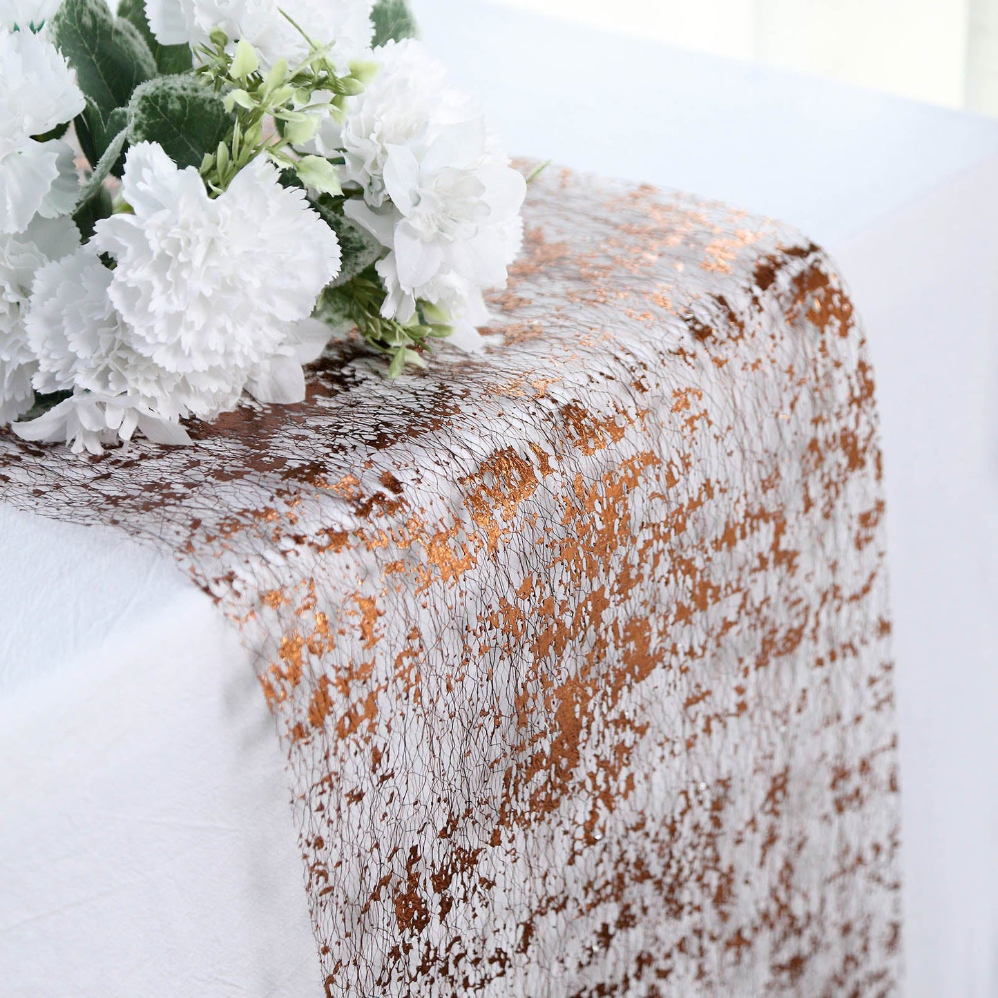 Sparkly metallic bronze foil disposable table runner on a white table.