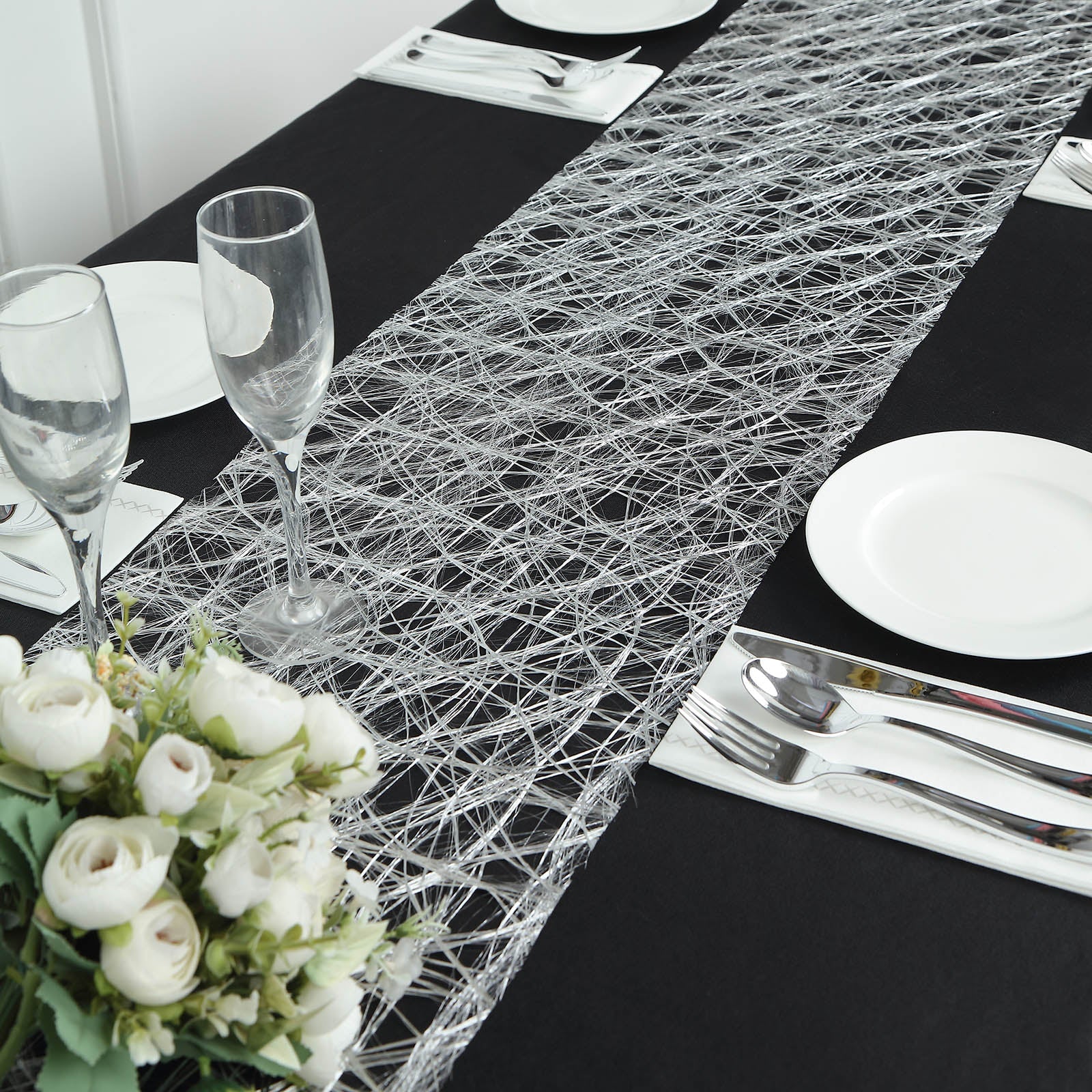 Metallic silver disposable table runner on a black table setting.