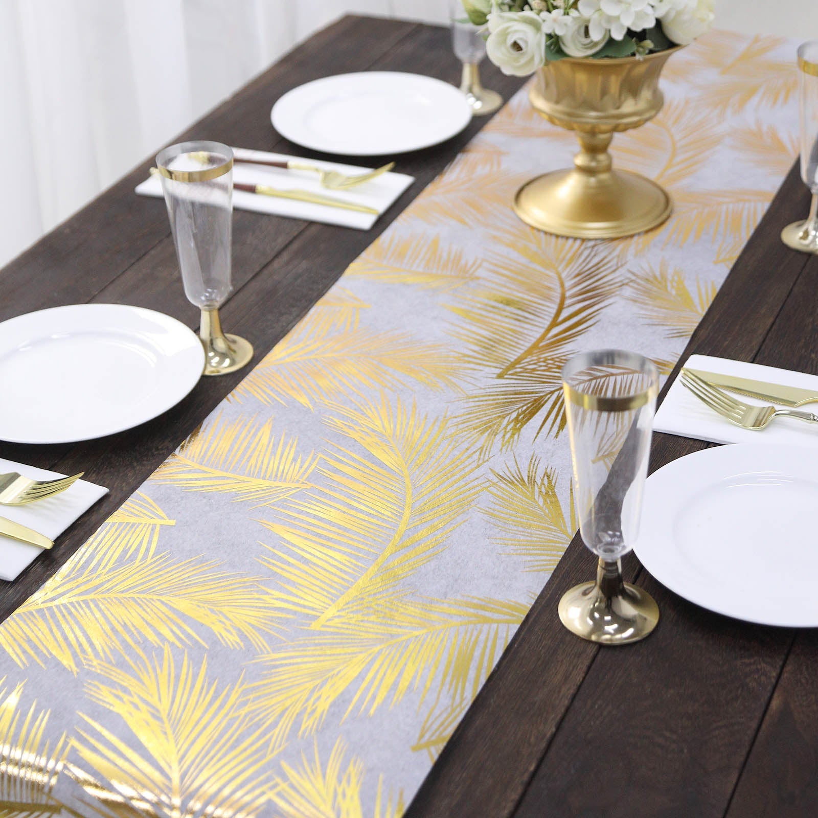 Metallic gold foil palm leaves table runner on a rustic wooden table.