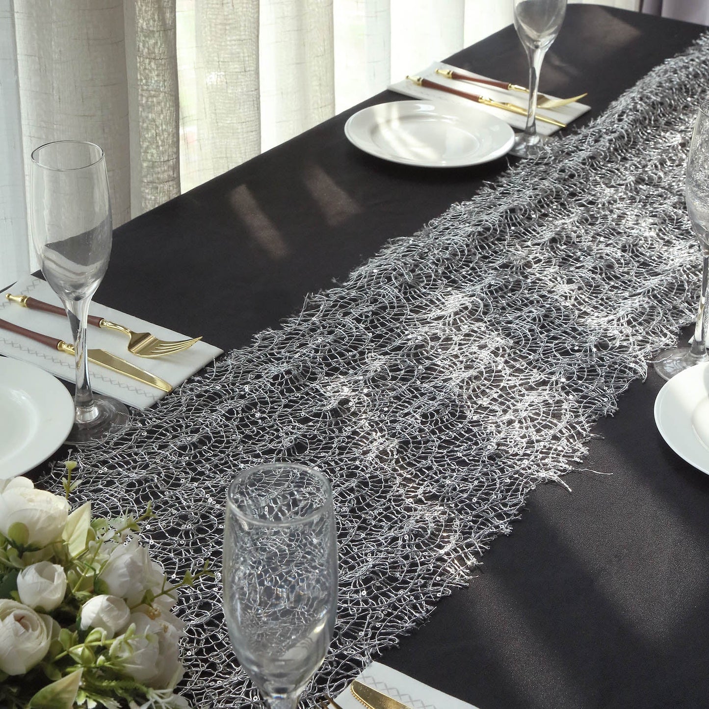 Silver sequin mesh lace table runner on a black table setting.