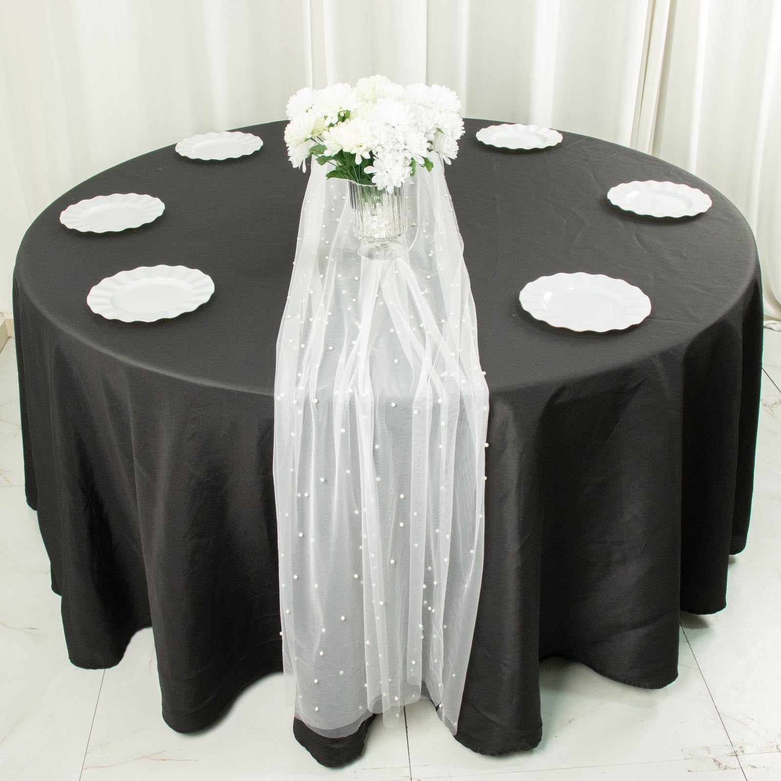 White pearl embellished sheer tulle table runner on a black tablecloth.