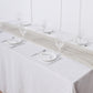 Beige chiffon table runner on a dining table setting with glasses and plates.