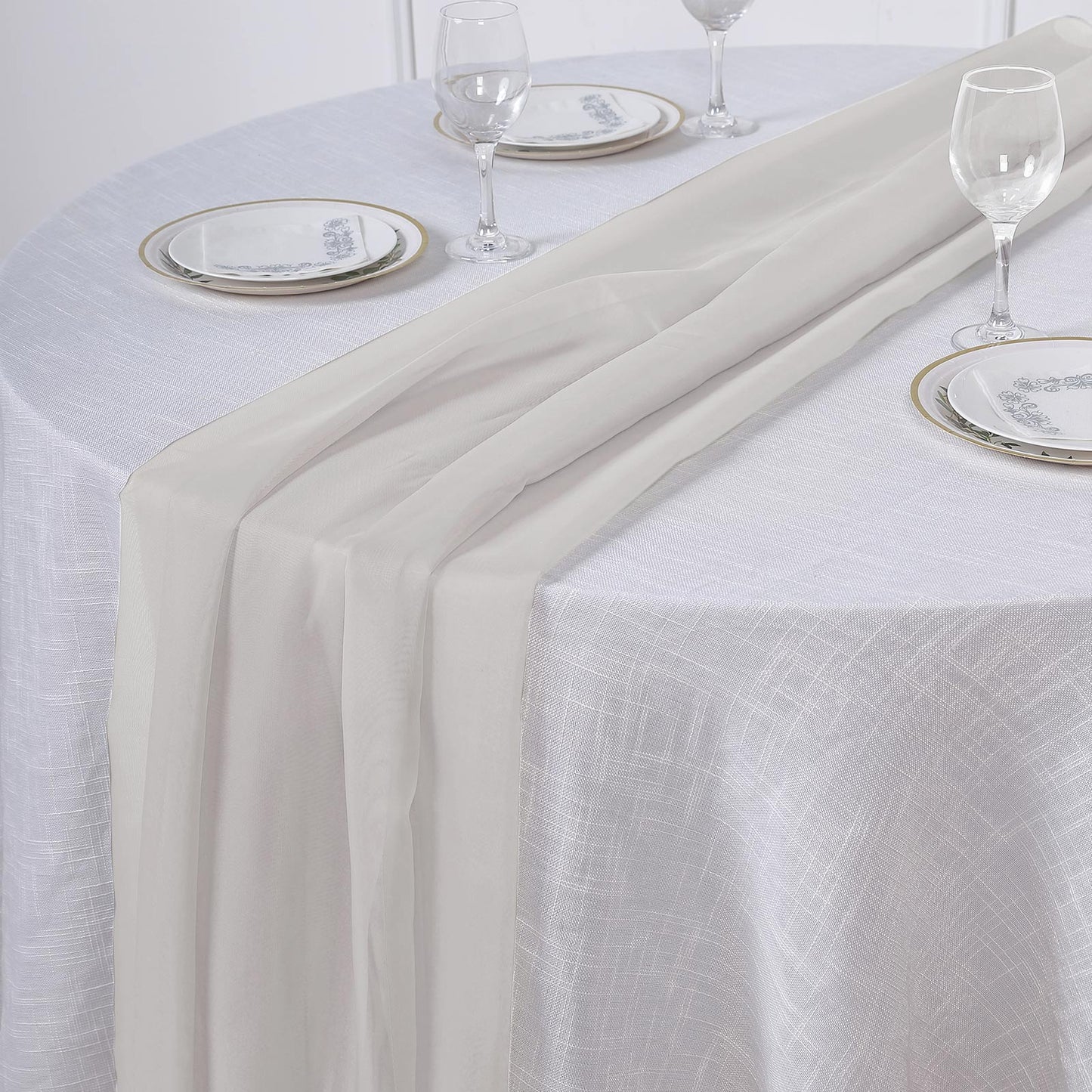 Beige chiffon table runner on a round table setting.