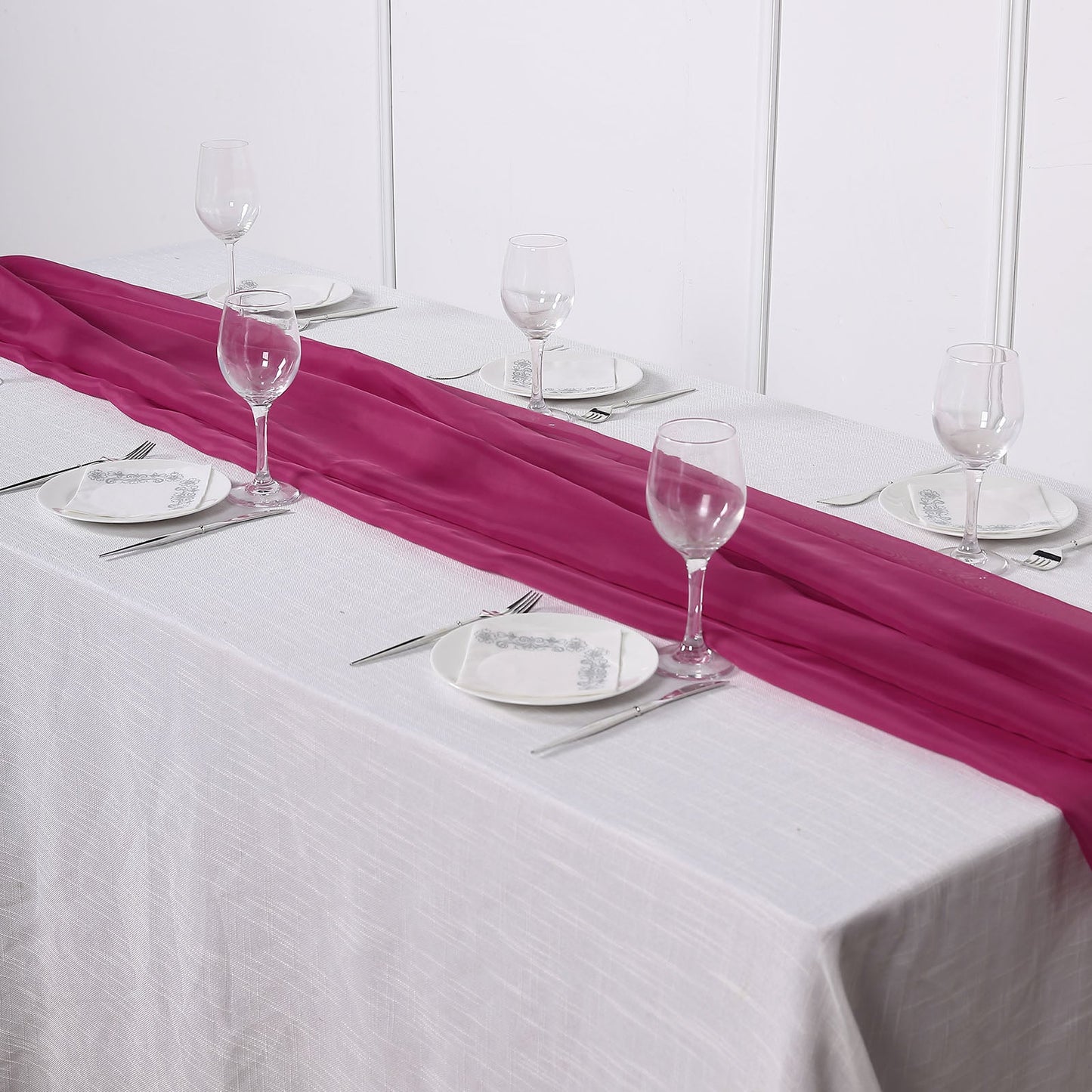 Fuchsia chiffon table runner on a white table setting.