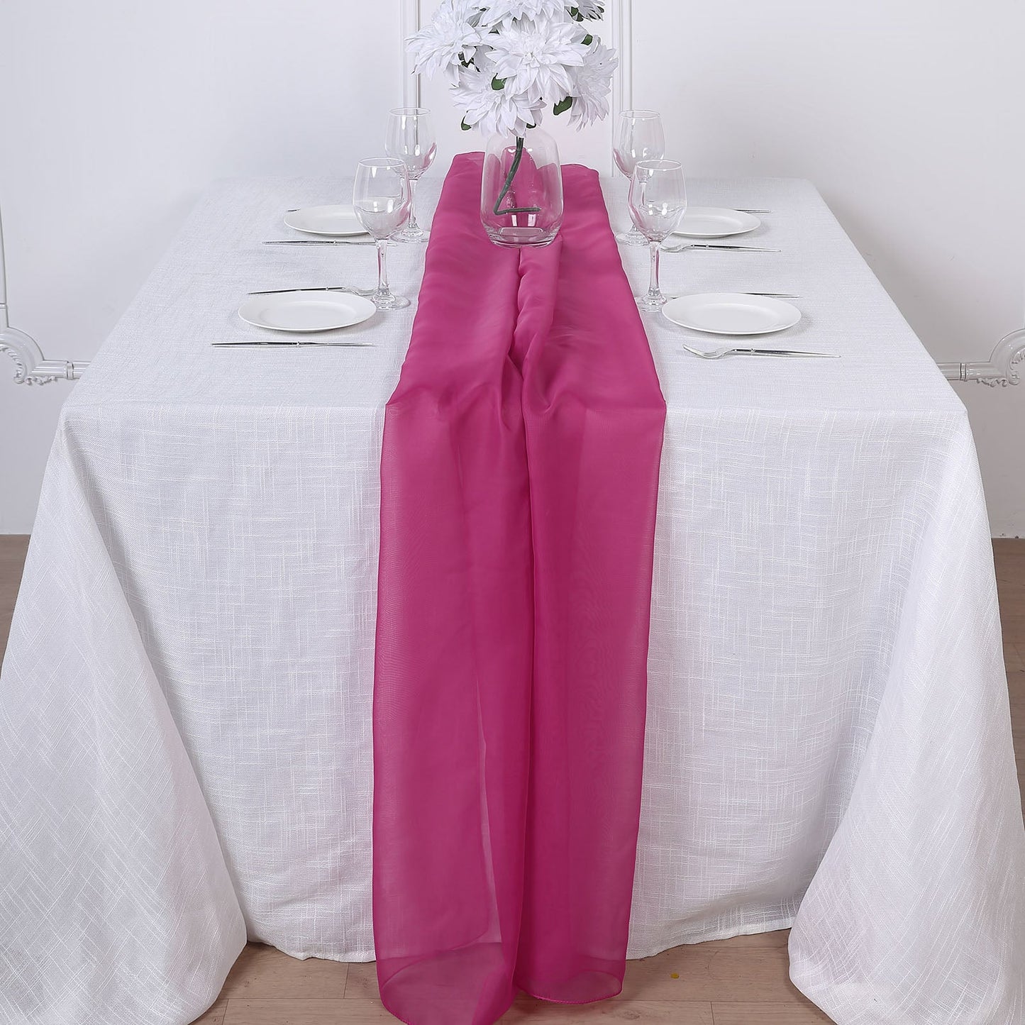 Fuchsia chiffon table runner on a white table setting.