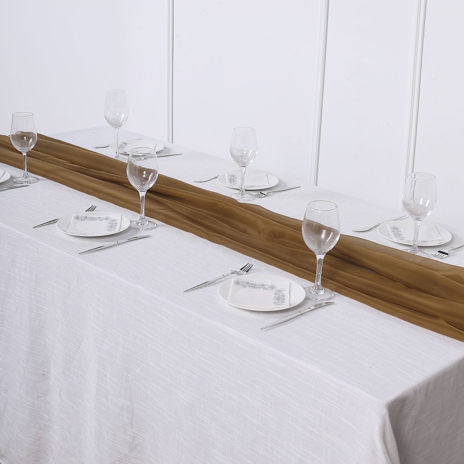 Gold chiffon table runner on a white table setting.