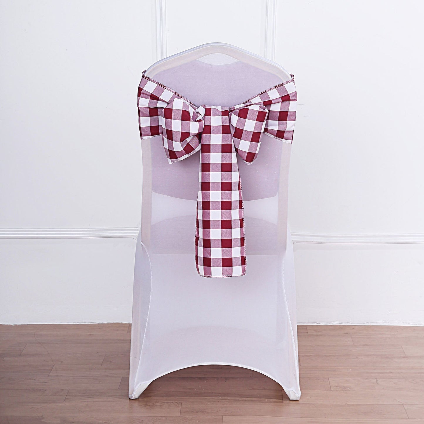 Burgundy and white checkered chair sash tied on a chair.