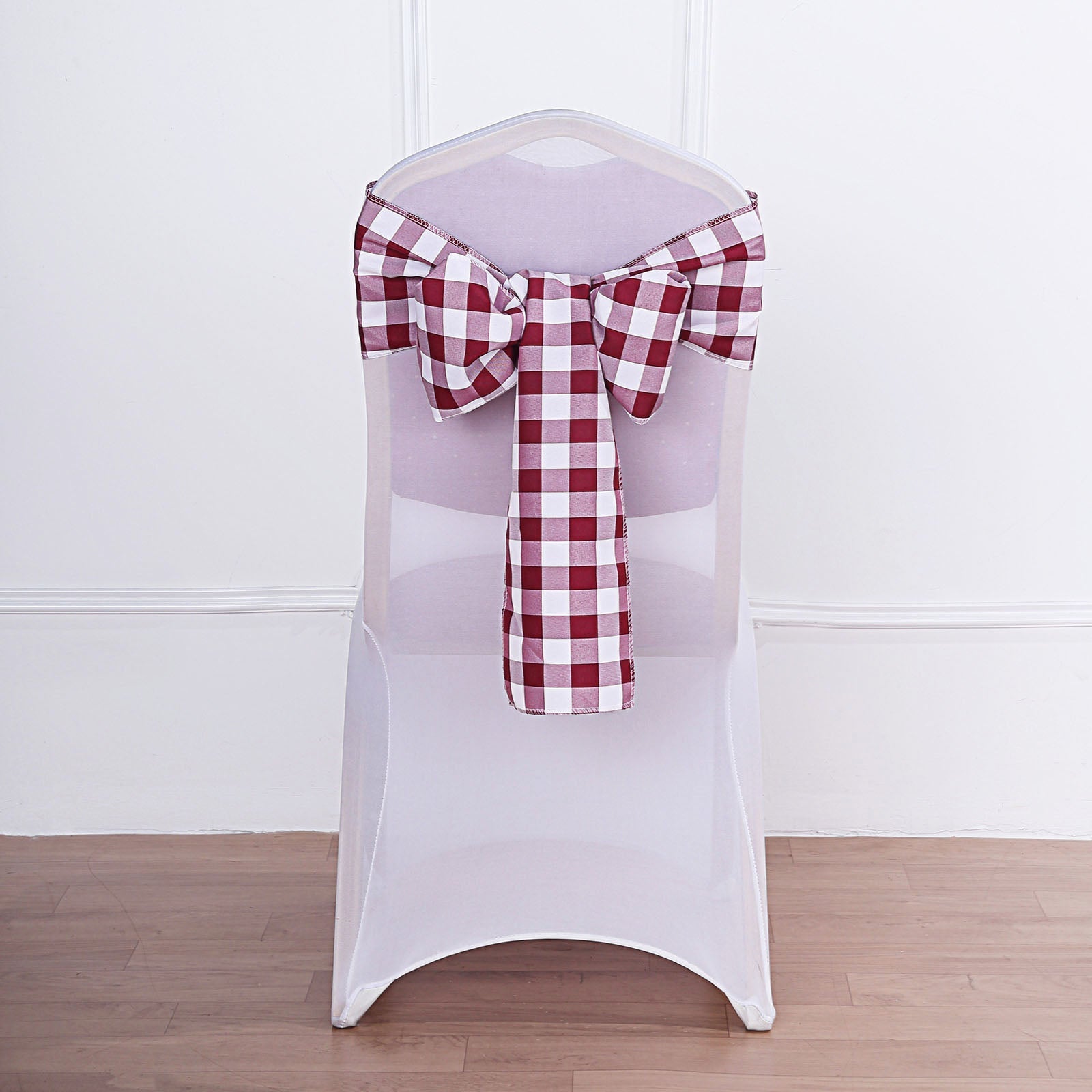 Burgundy and white checkered chair sash tied on a chair.