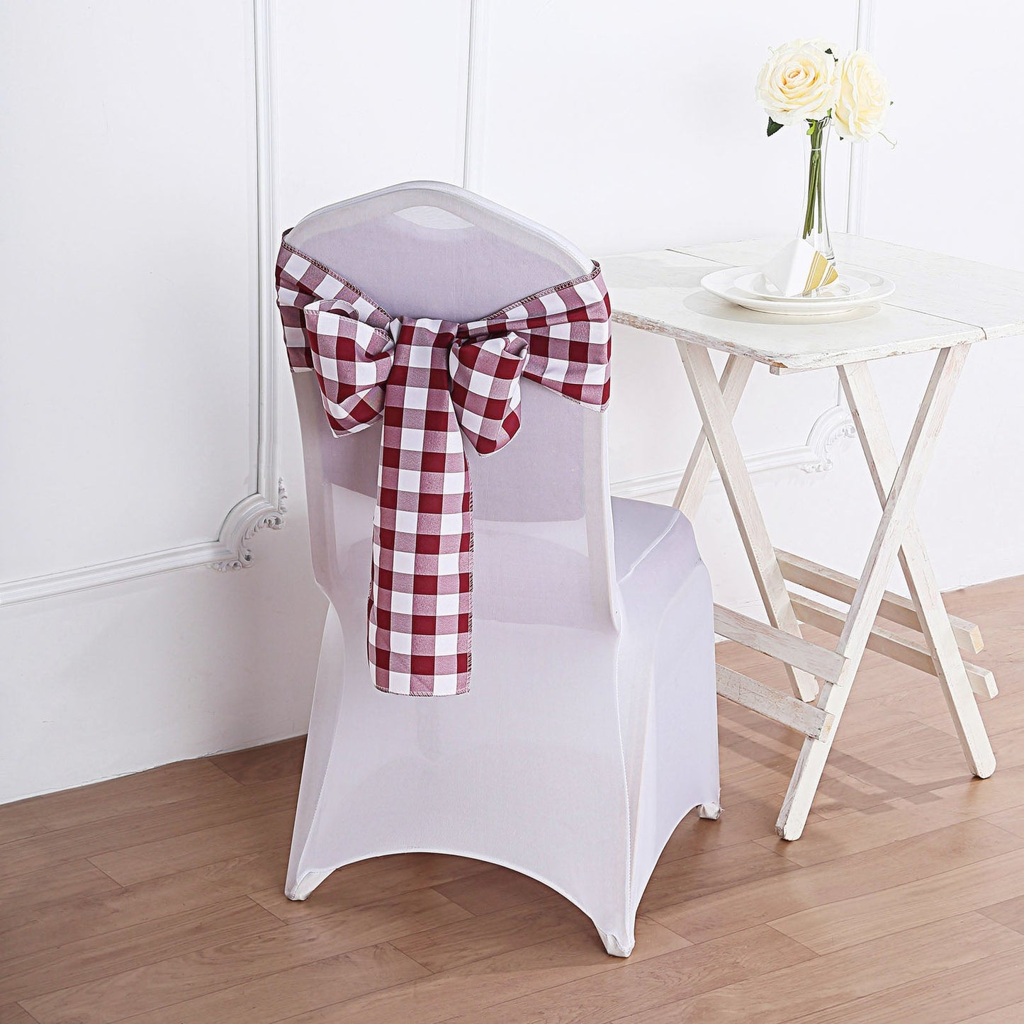 Burgundy and white checkered chair sashes on a white chair.
