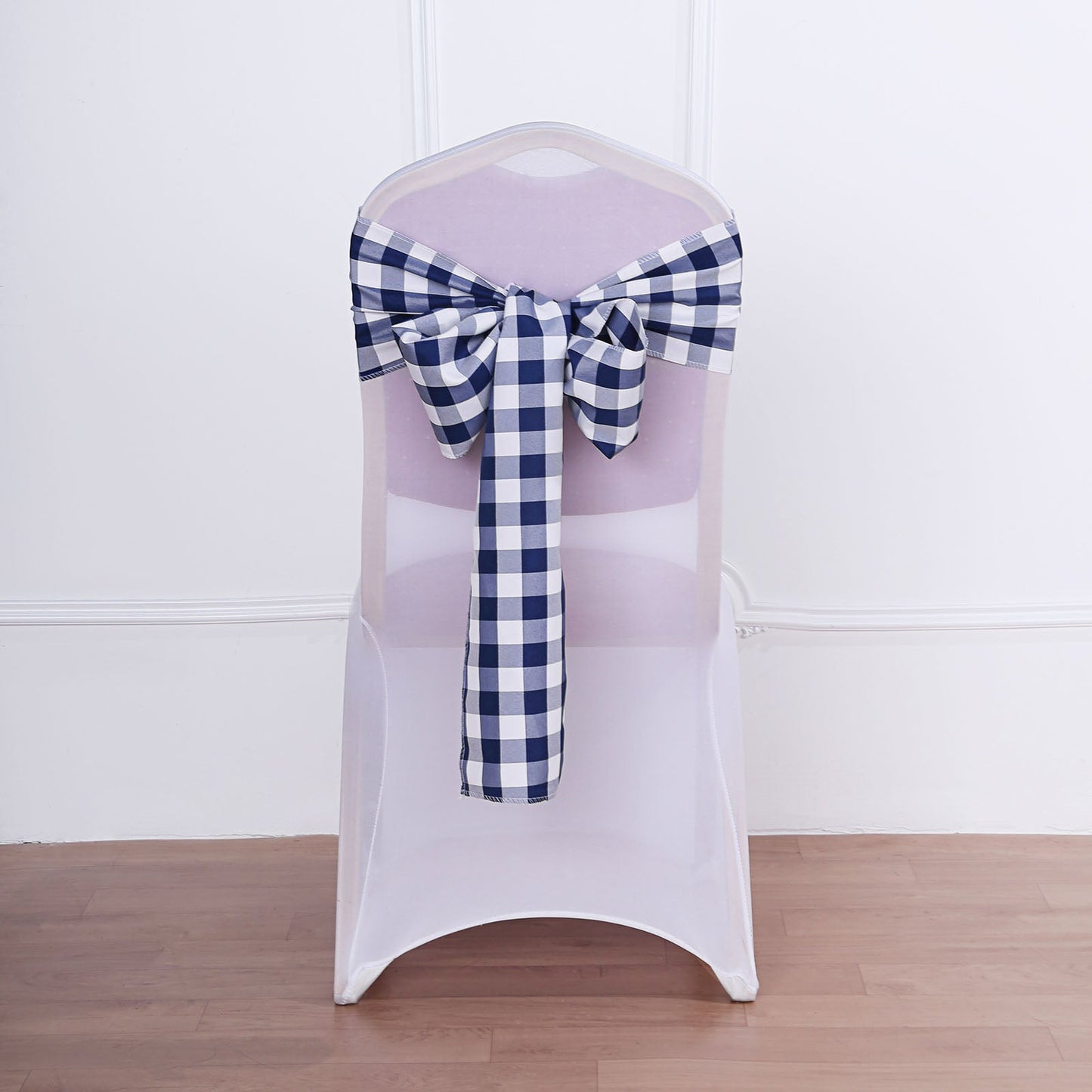Navy blue and white checkered chair sash tied on a white chair.