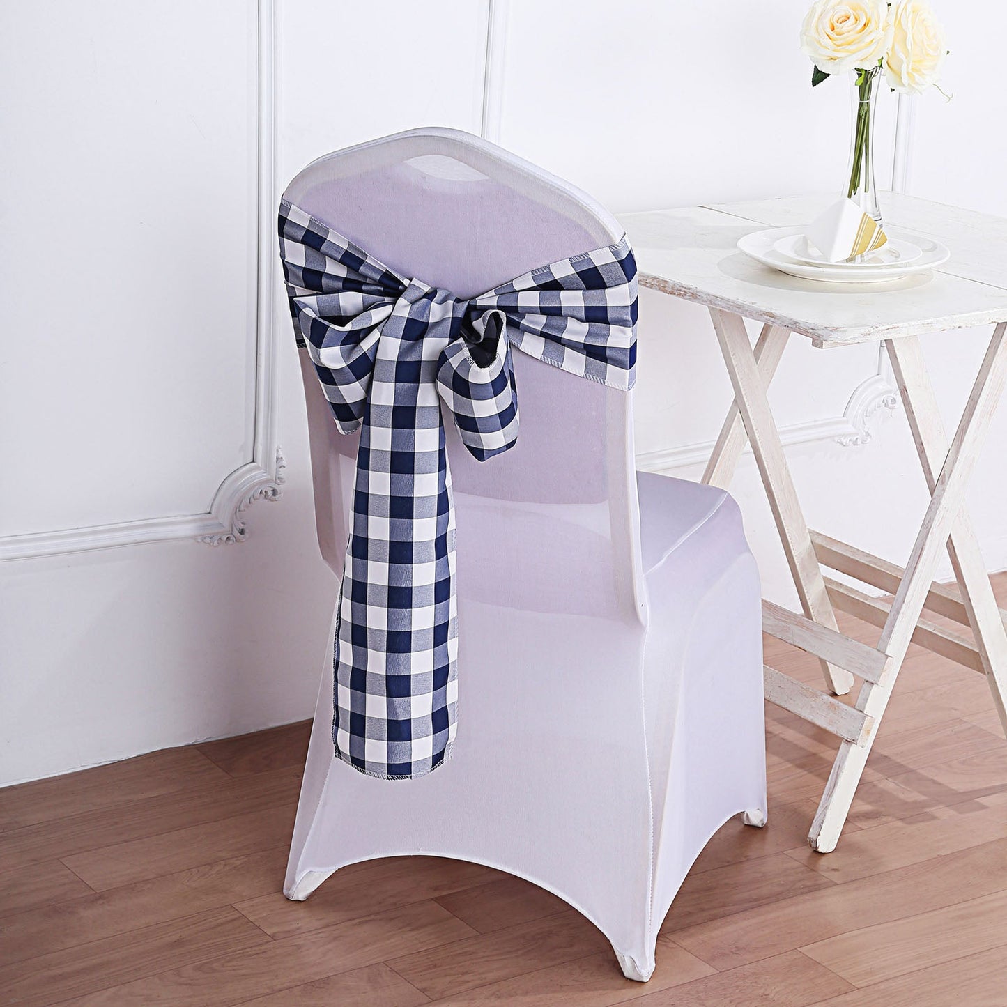 Navy blue and white checkered chair sash tied on a white chair.