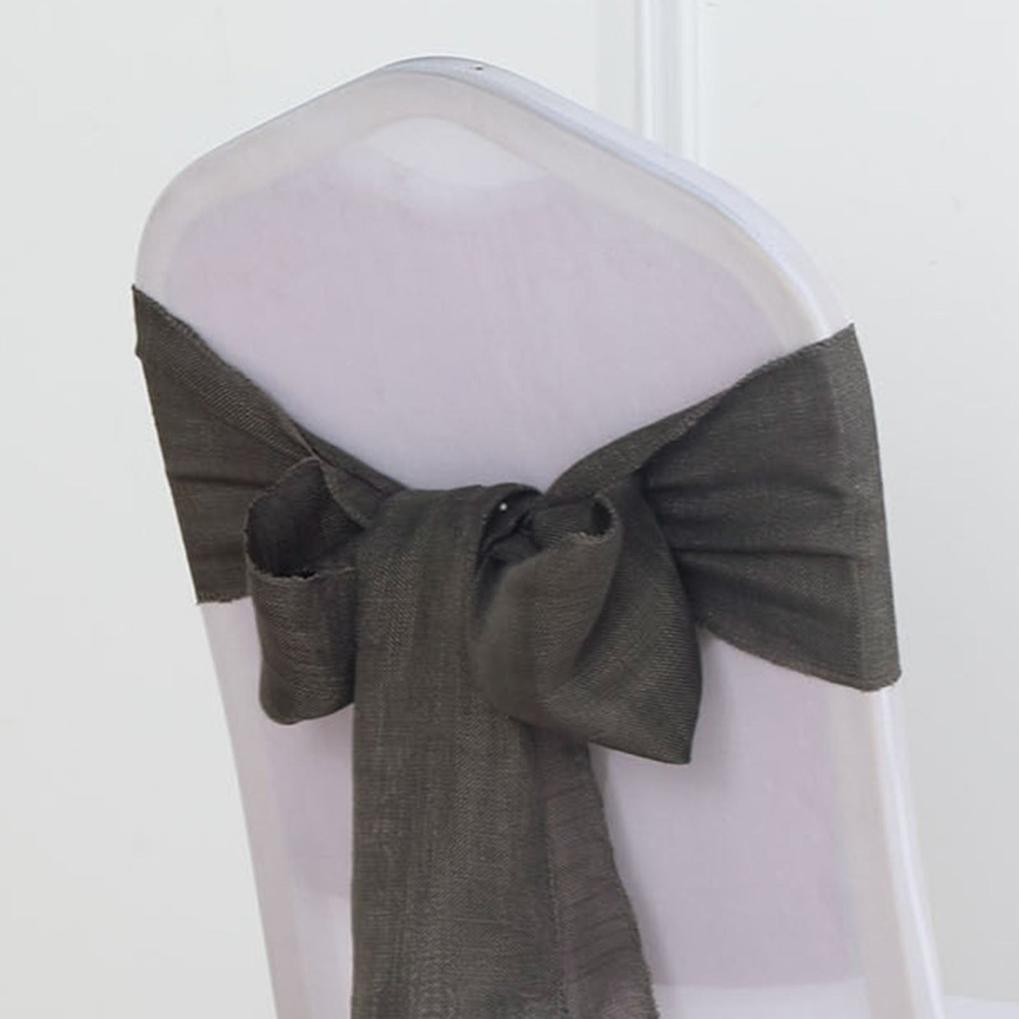 Charcoal gray linen chair sash tied in a bow on a transparent chair.