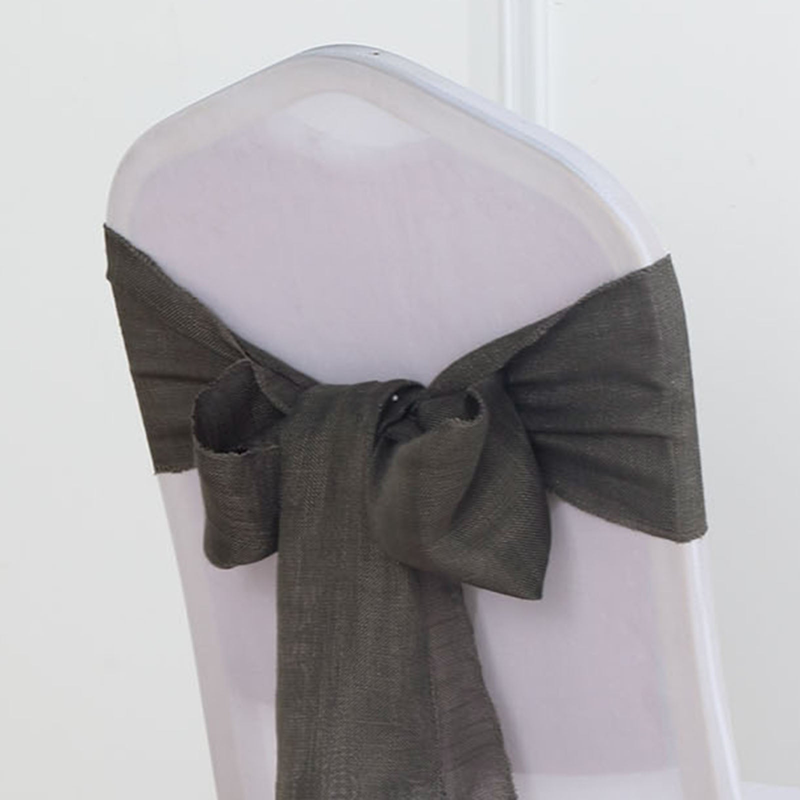 Charcoal gray linen chair sash tied in a bow on a transparent chair.
