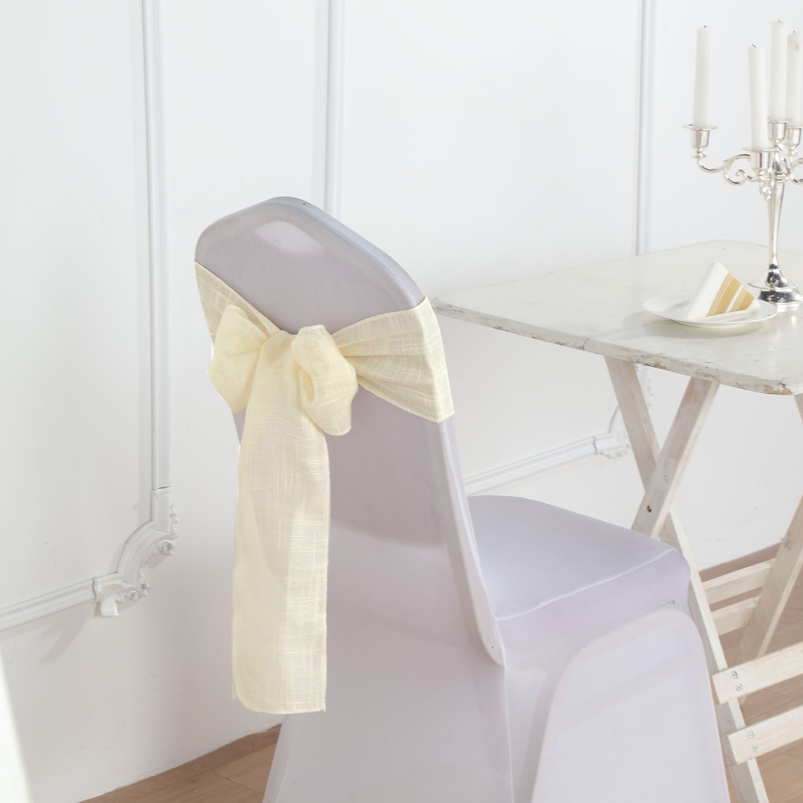 Ivory linen chair sash tied in a bow on a clear chair.