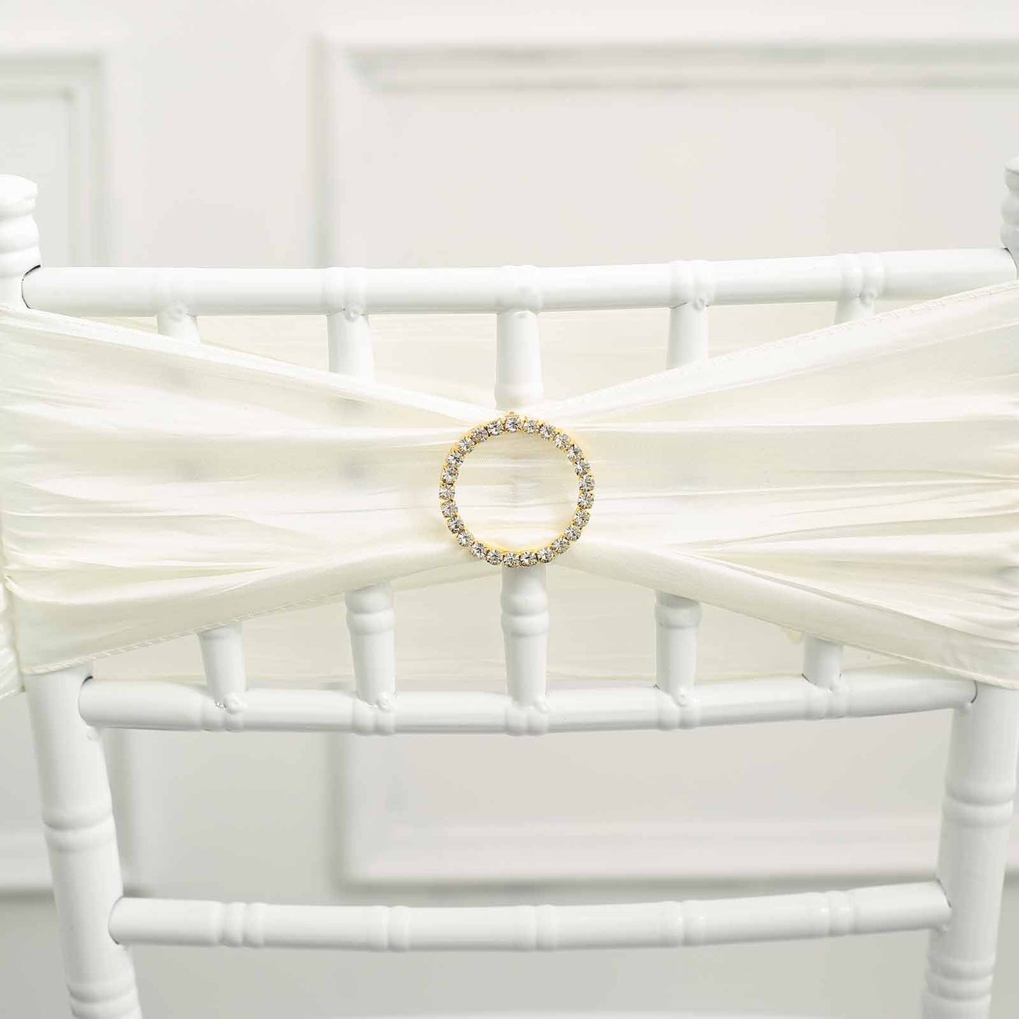 Gold rhinestone circle buckle on white chair sash.