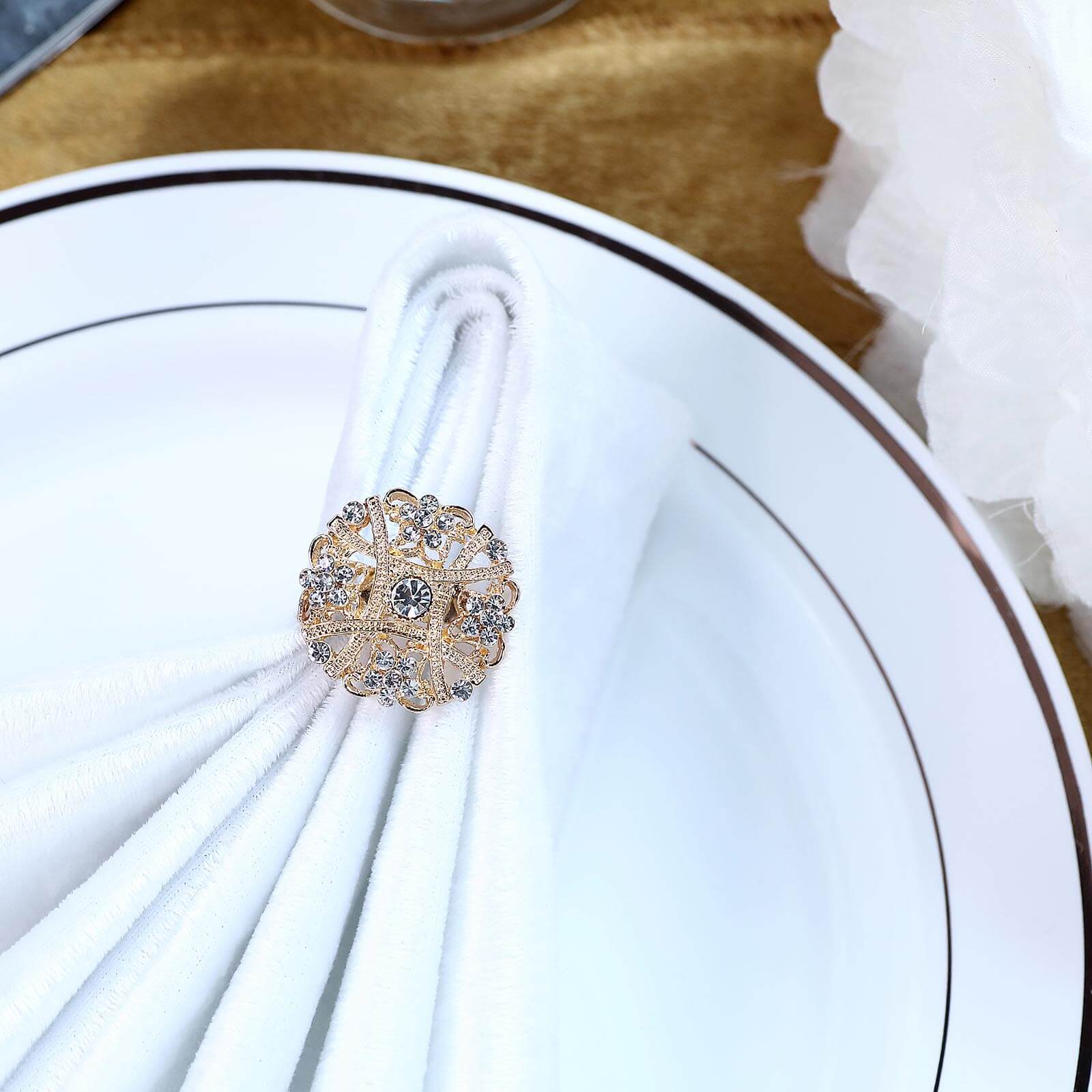 Gold-plated mandala brooch with rhinestones on a white napkin.