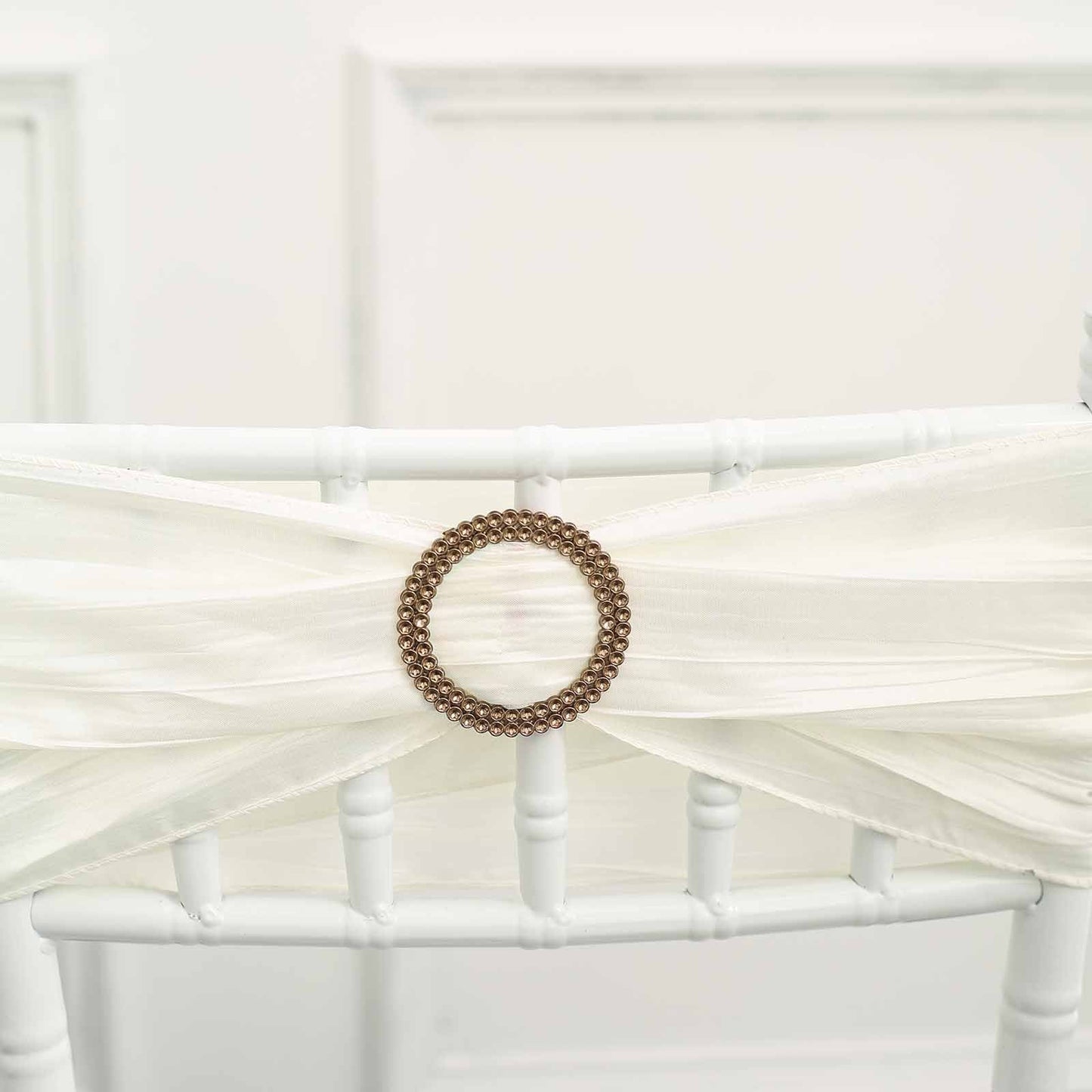 Antique gold diamond circle chair sash band buckle pin on a white chair.