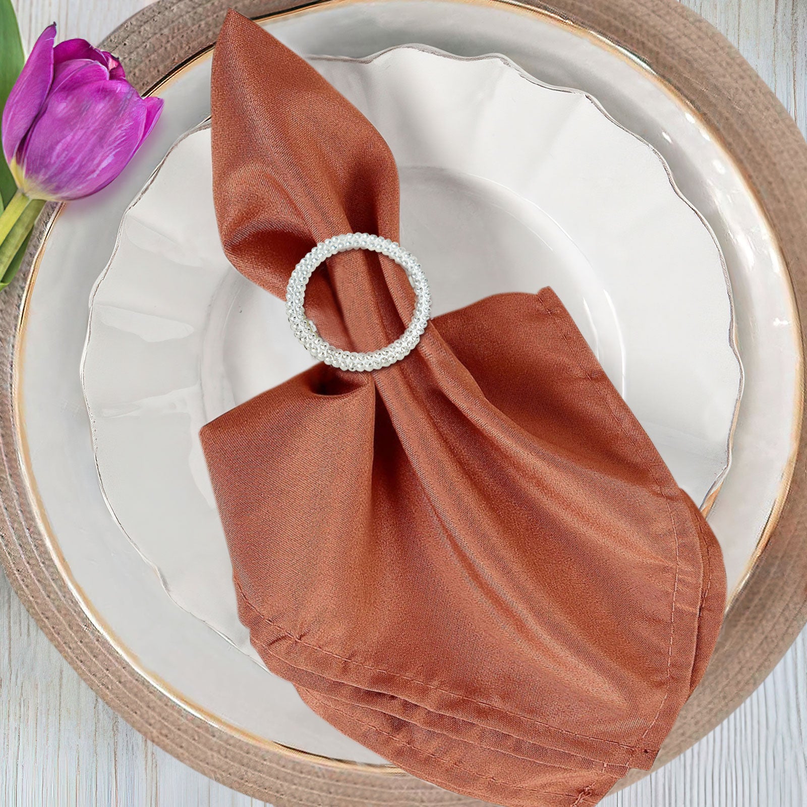 Silver rhinestone napkin ring brooch on a brown napkin.
