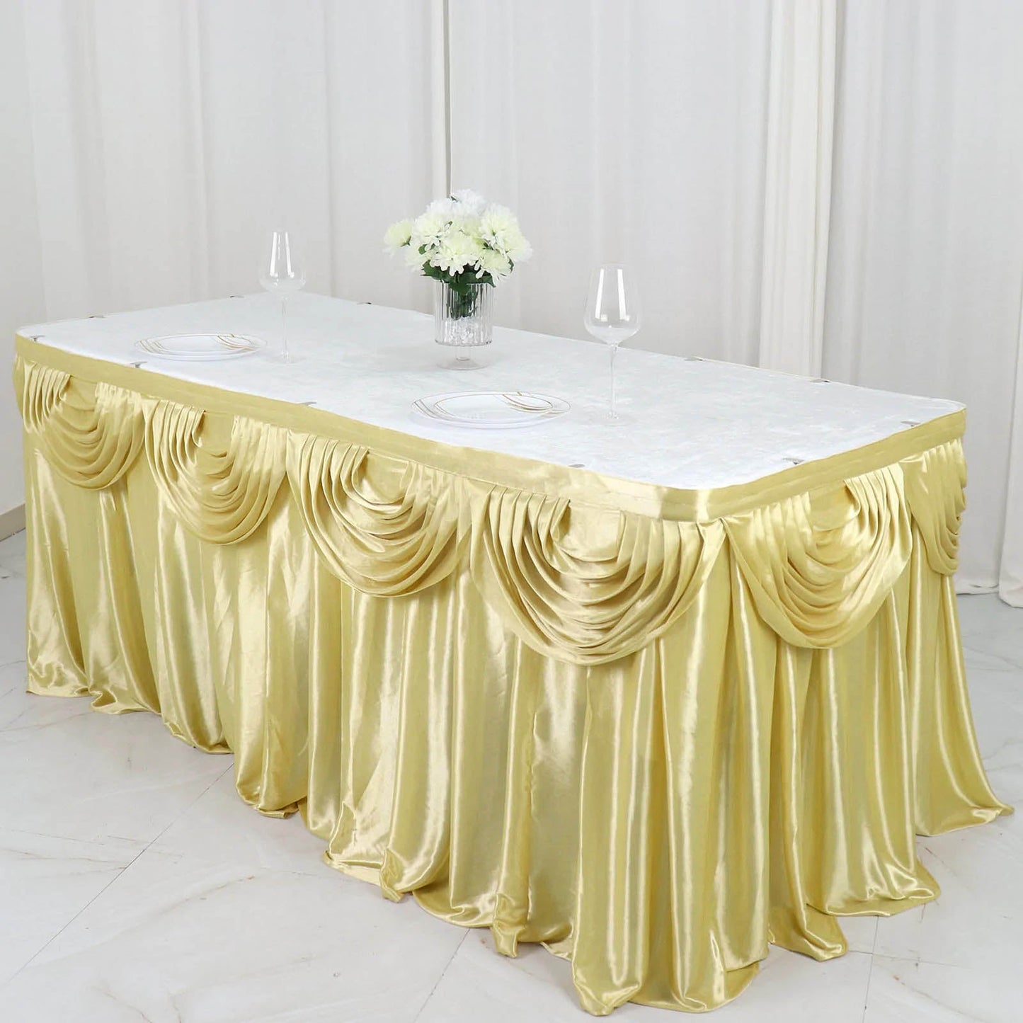 Champagne pleated satin table skirt draped elegantly on a table.