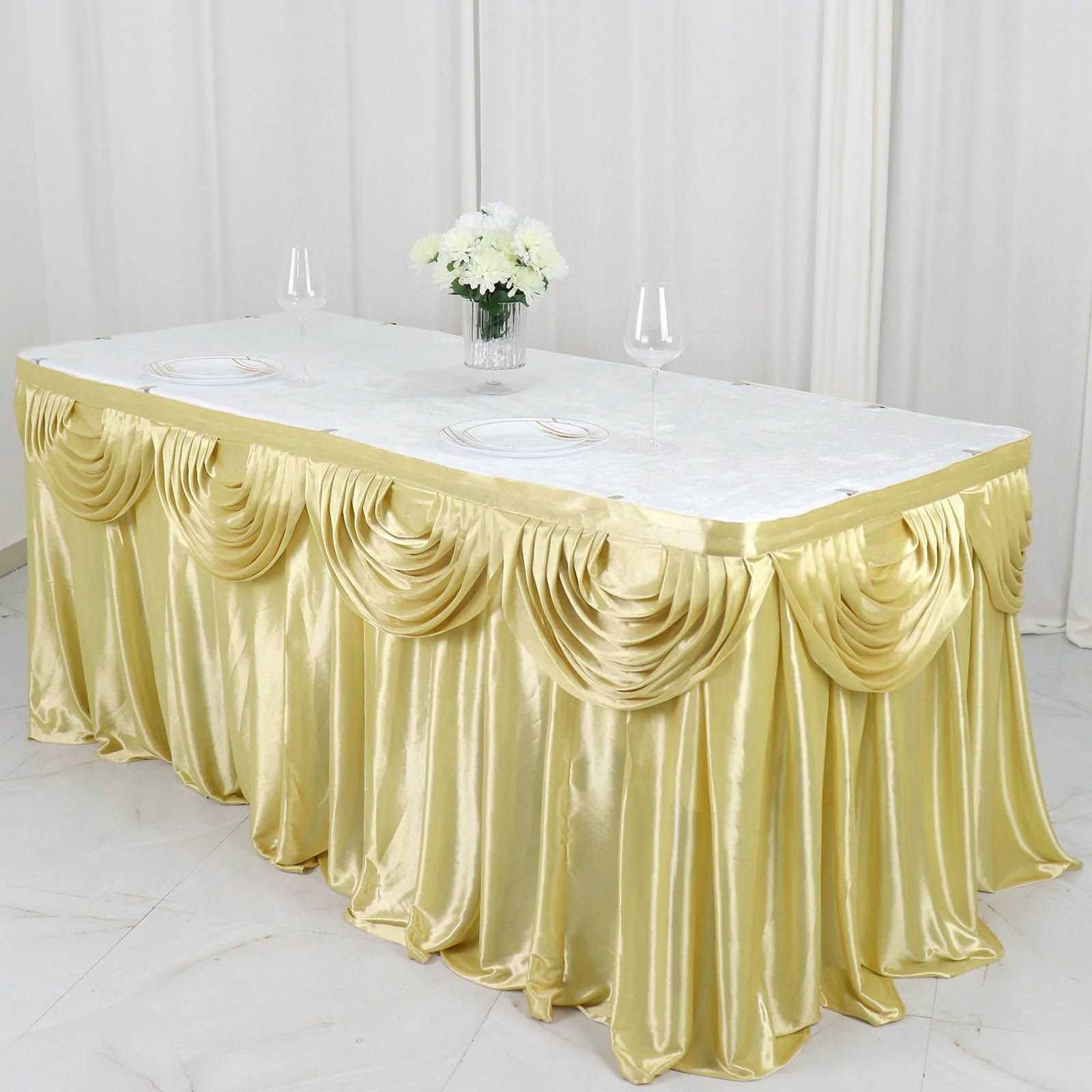 Champagne pleated satin table skirt draped elegantly on a table.