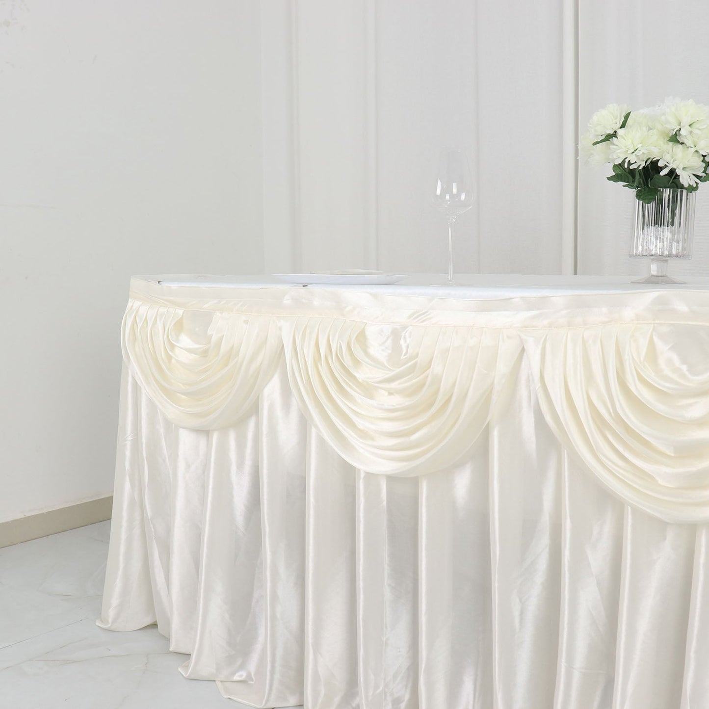 Ivory pleated satin table skirt draped elegantly on a table.