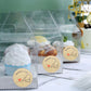 Baked with love stickers on clear bakery boxes with cupcakes and pastries.