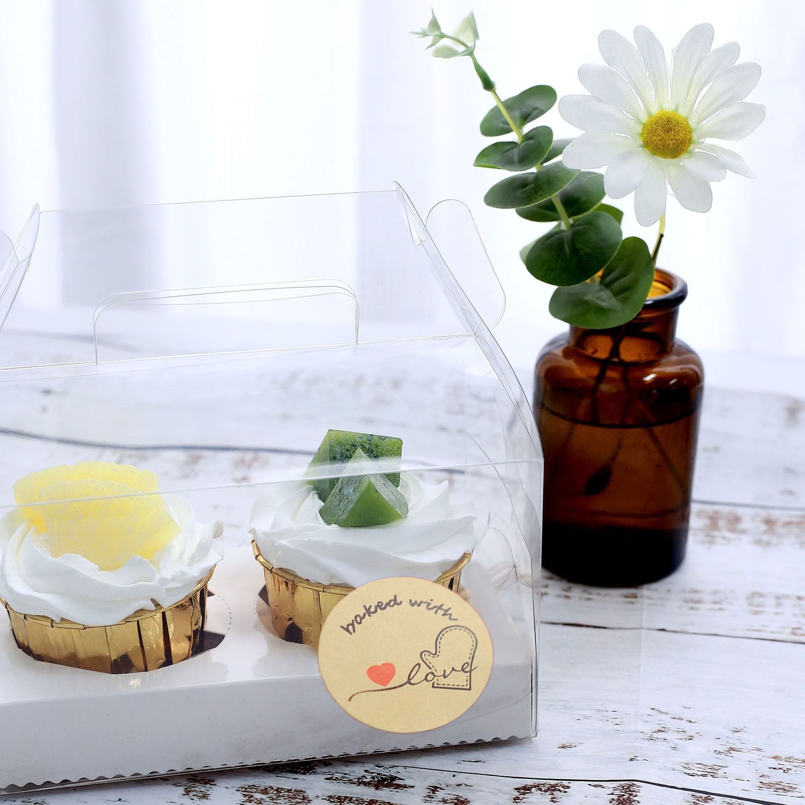 Baked with love stickers on bakery box with yellow and green cupcakes.