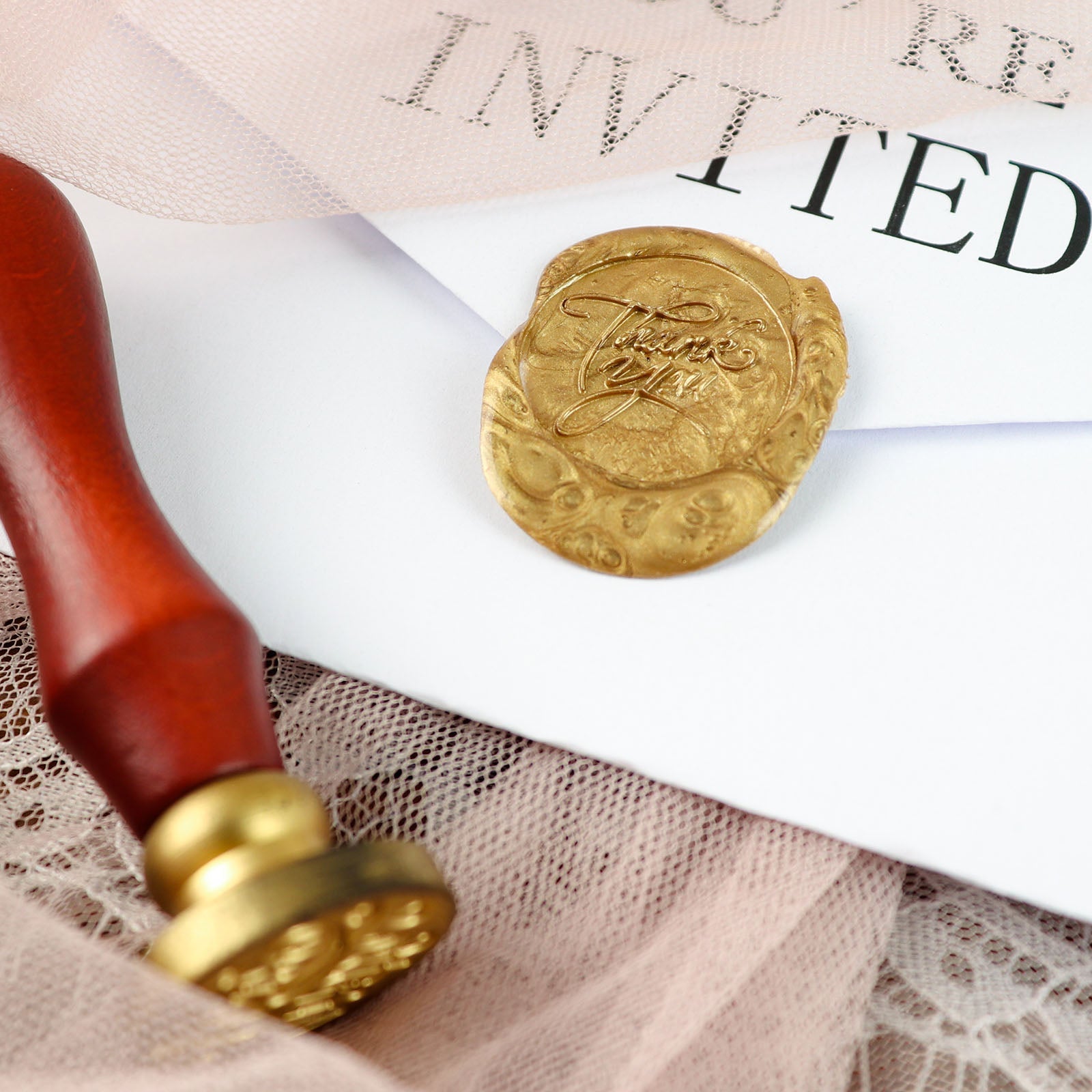 Gold wax seal stamp on a wedding invitation envelope.
