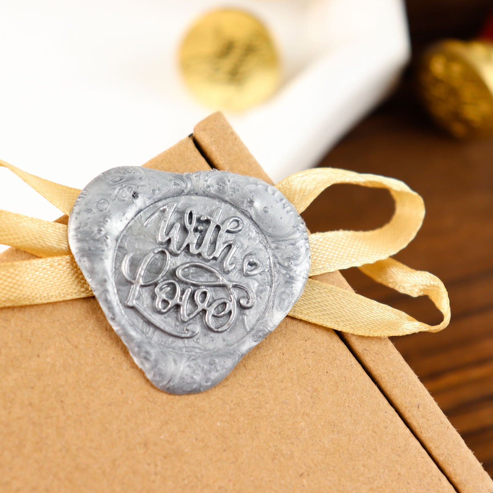 Silver wax seal stamp with "With Love" on a gift box.