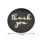Gold foil "Thank You" sticker on black background, 1.5 inches round.