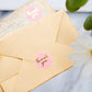 Pink round stickers with gold foil "Thank You" text on an envelope.