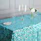 Turquoise sequin tablecloth on a dining table with candles and flowers.