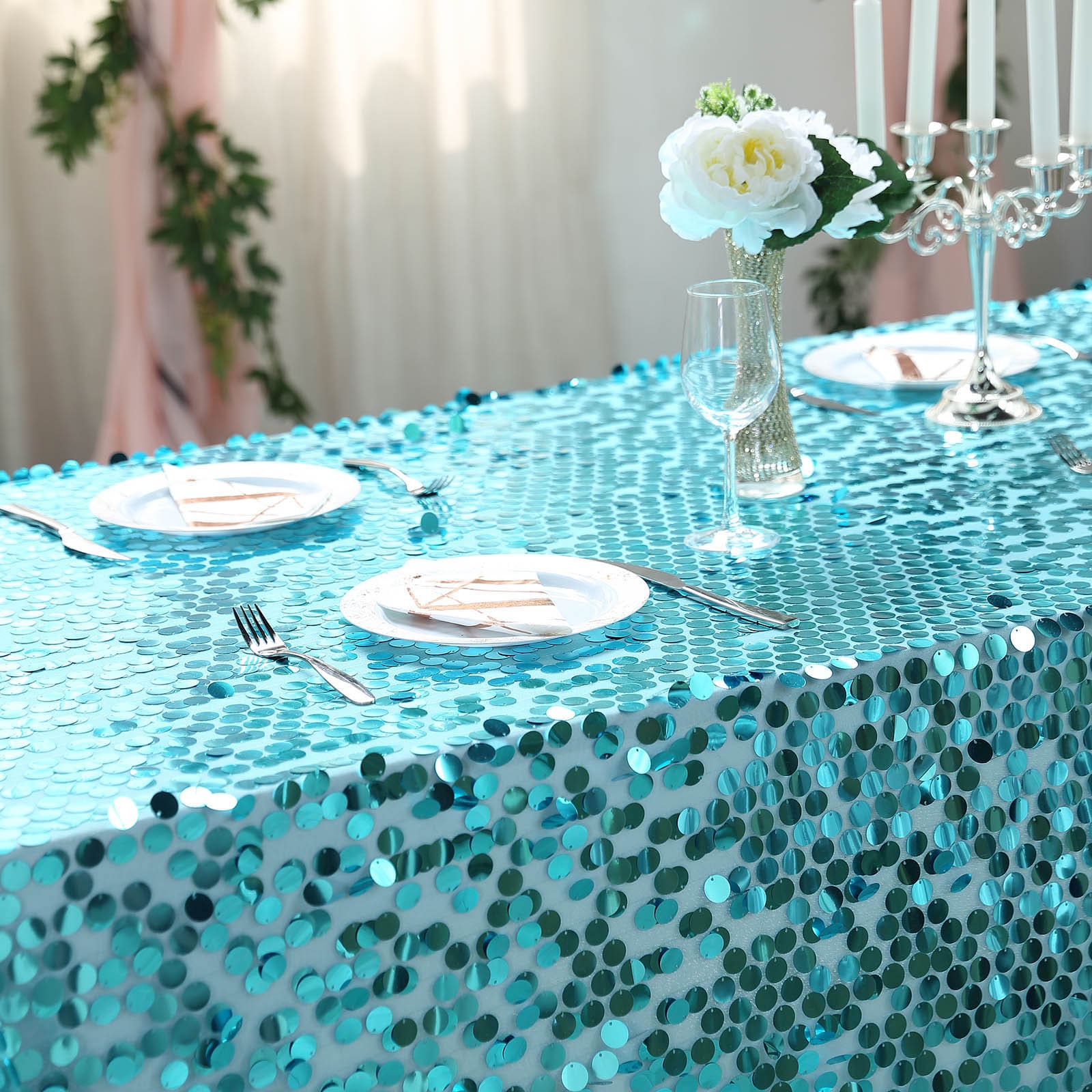 Turquoise sequin tablecloth on a decorated dining table.