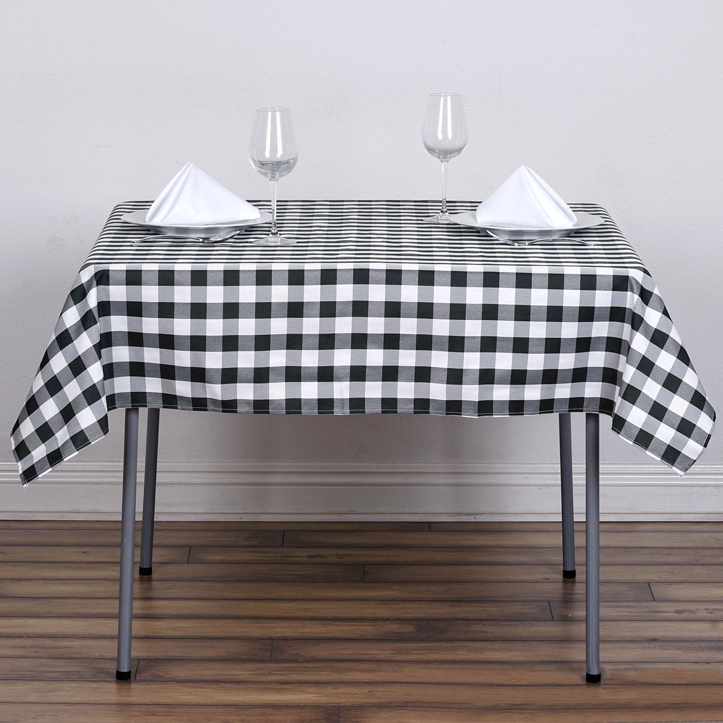 White and black buffalo plaid square table overlay on a dining table.