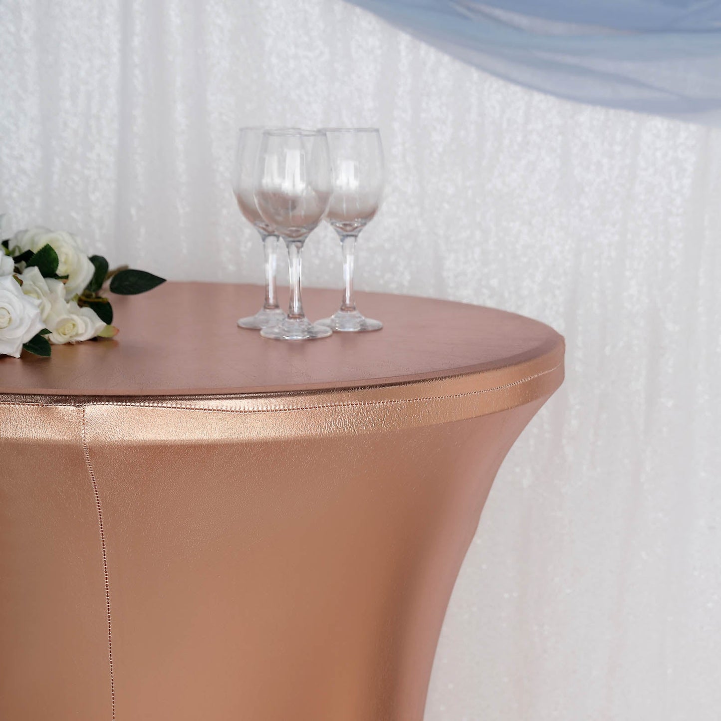 Blush metallic fitted cocktail table cover with glasses on top.