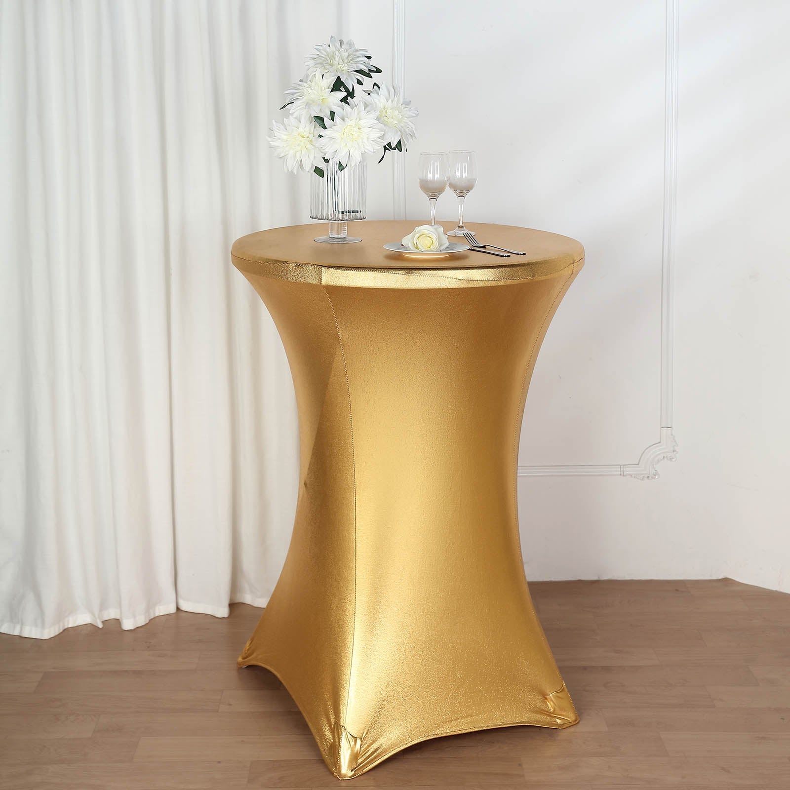 Gold fitted round cocktail table cover on a highboy table.