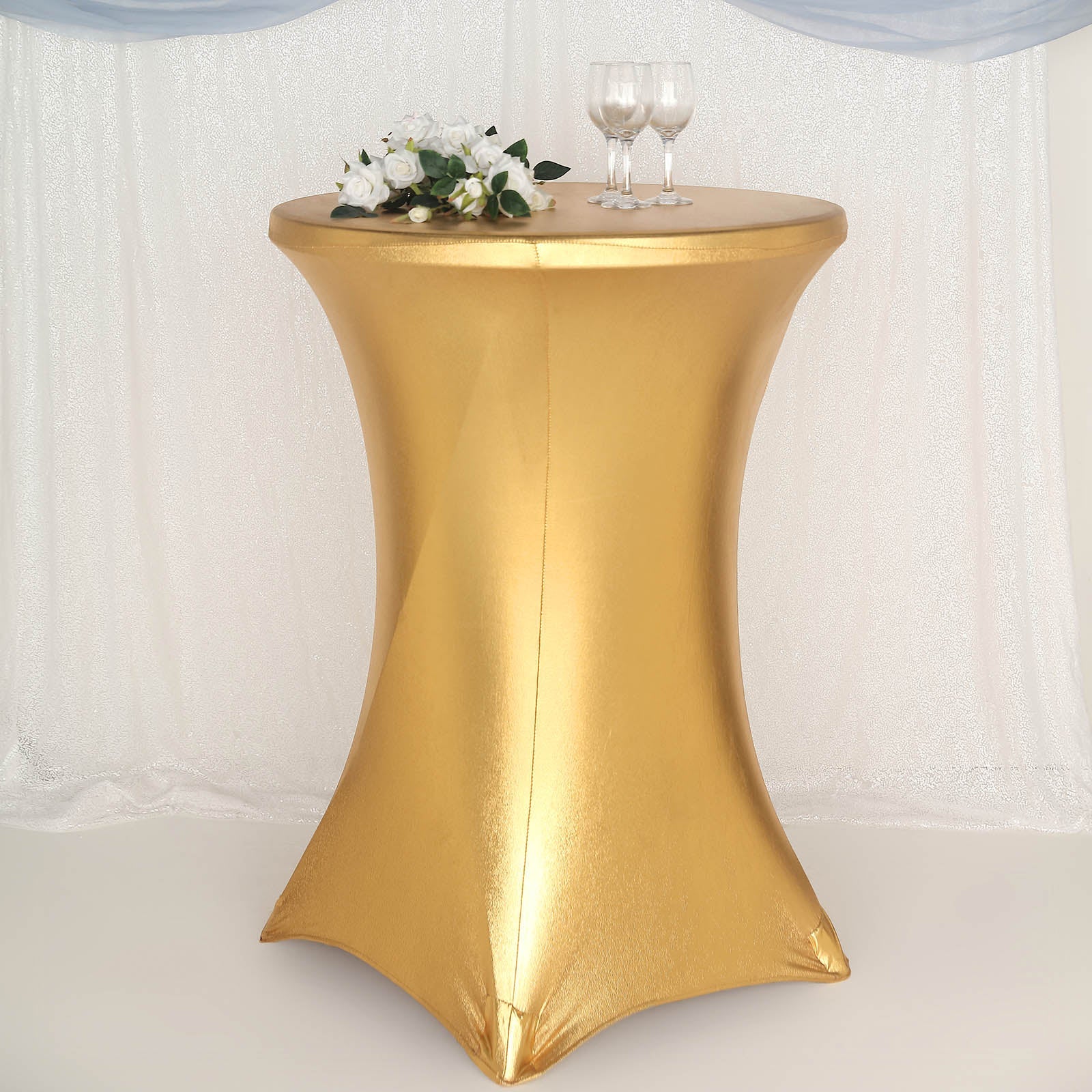 Gold fitted round cocktail table cover on a highboy table.