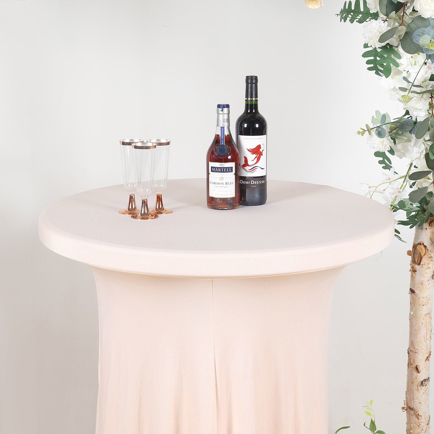 Blush round cocktail table cover with wavy drapes and drinks on top.
