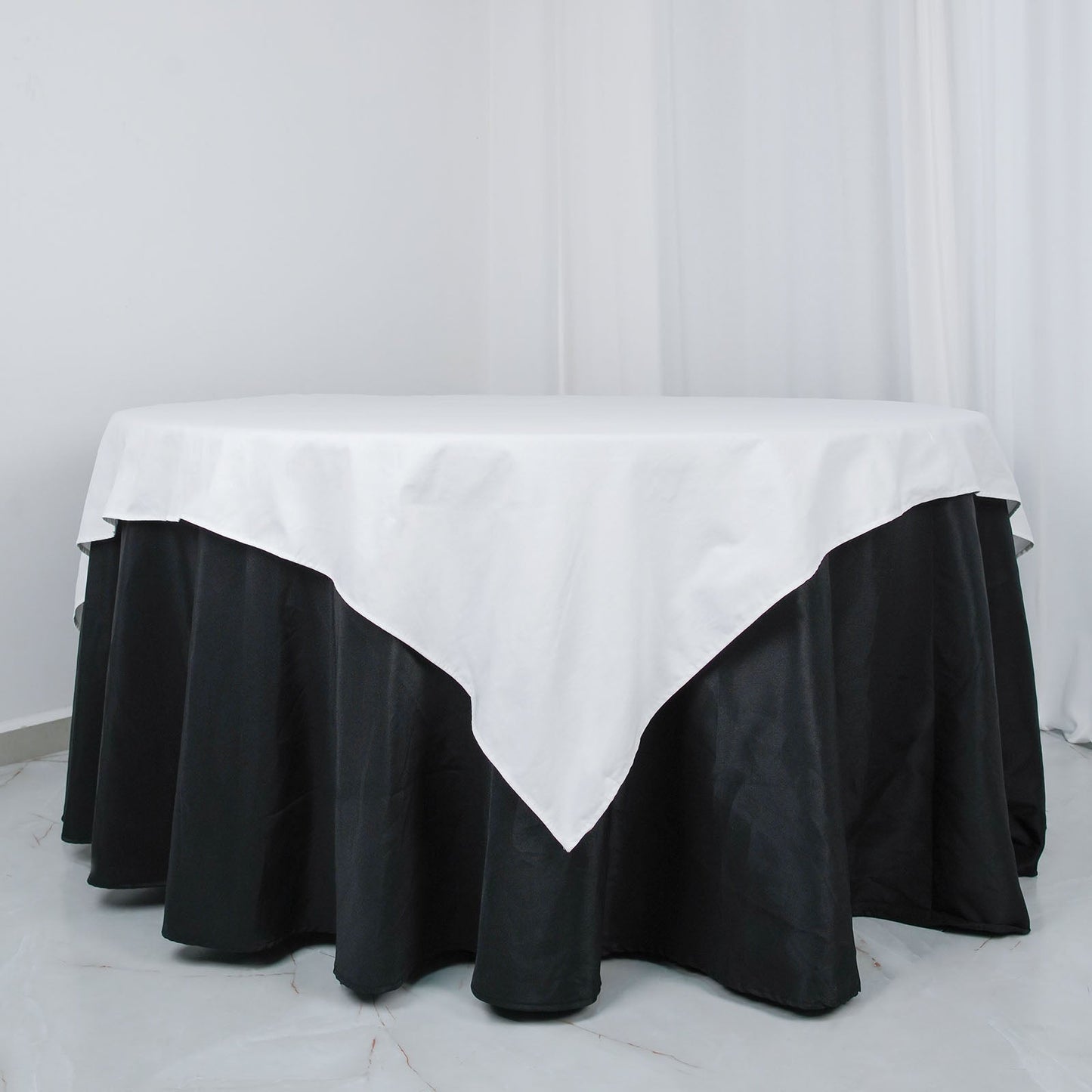 White square cotton linen table overlay on a black tablecloth.