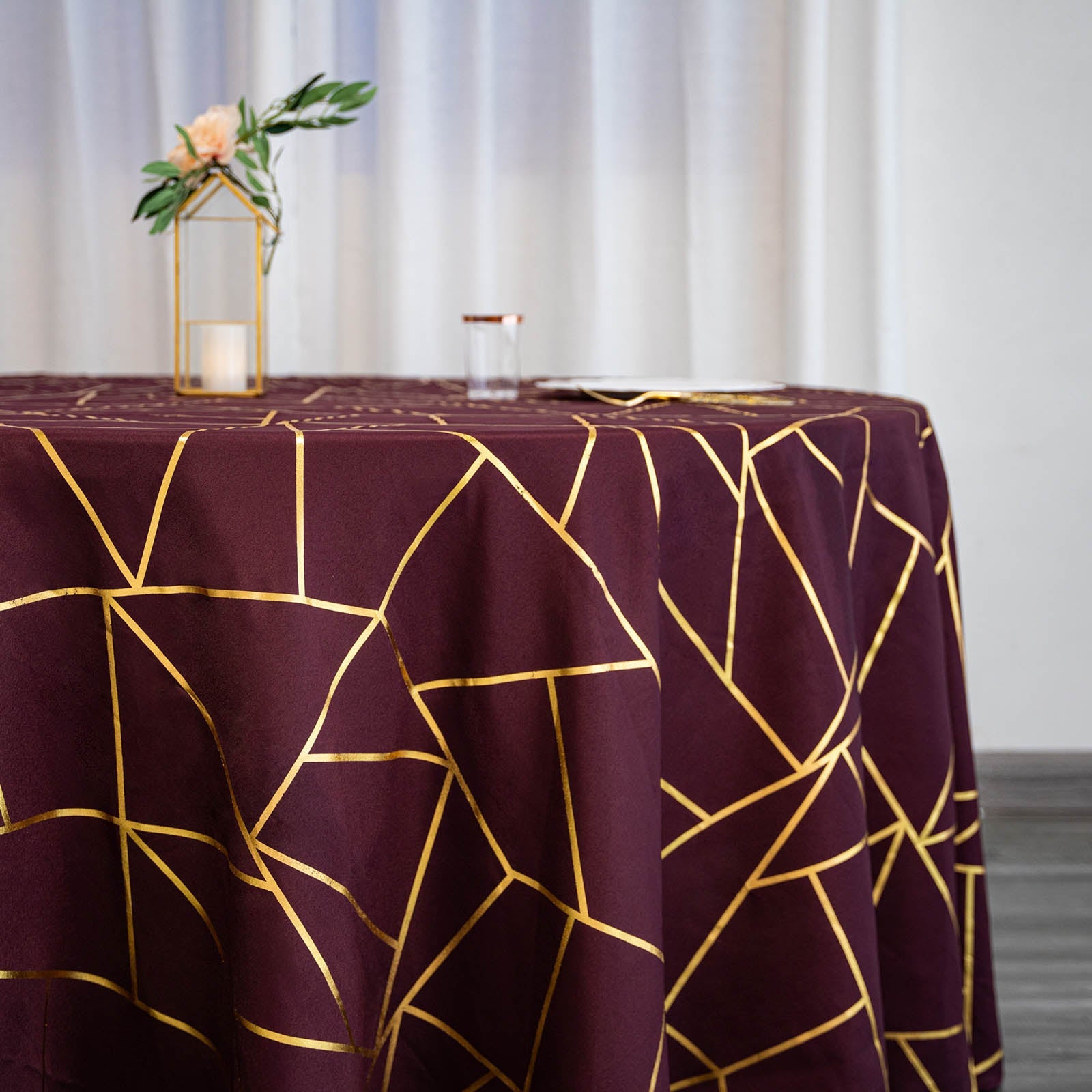 Burgundy tablecloth with gold foil geometric pattern on a table.