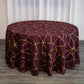 Burgundy round tablecloth with gold geometric pattern on a wooden floor.